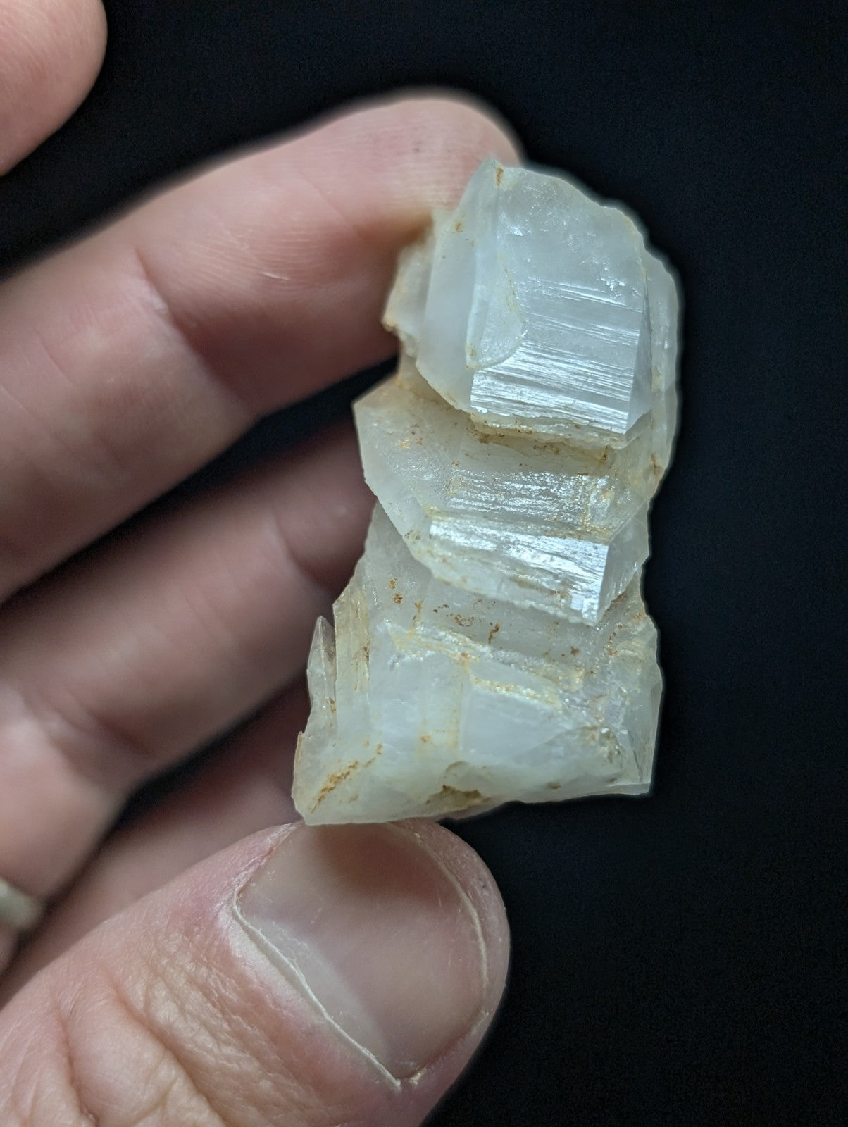 A translucent, pale white mineral specimen with distinct crystalline facets and a slightly rough, natural surface.