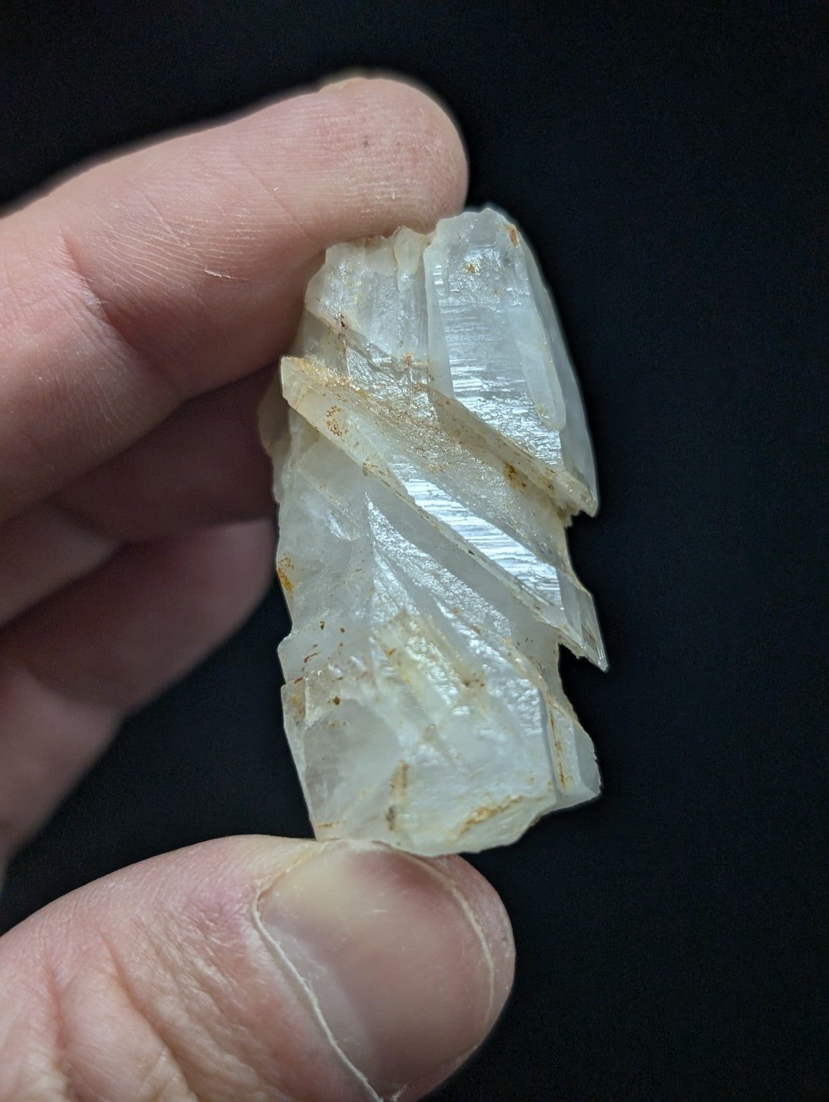 A translucent white quartz crystal with visible striations and minor golden inclusions.