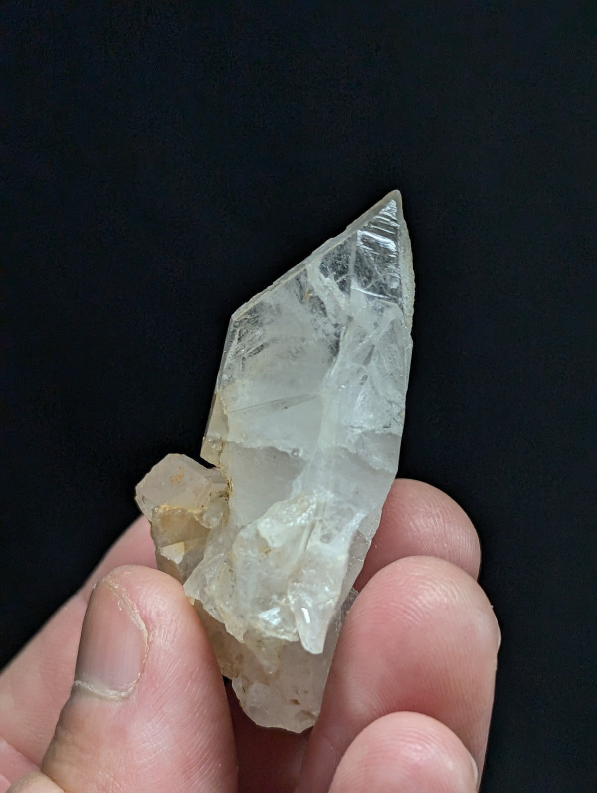 A translucent, clear quartz crystal with a pointed tip and natural facets.