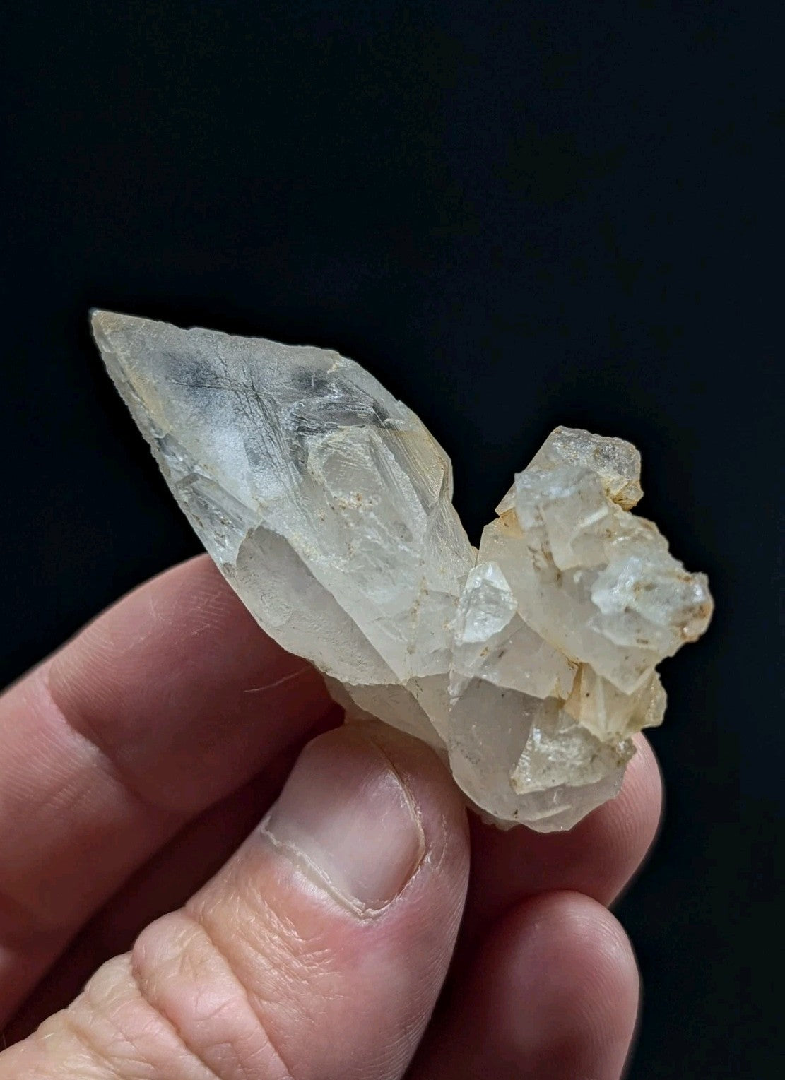 A translucent, pale yellow quartz crystal cluster with a pointed tip and rougher base.