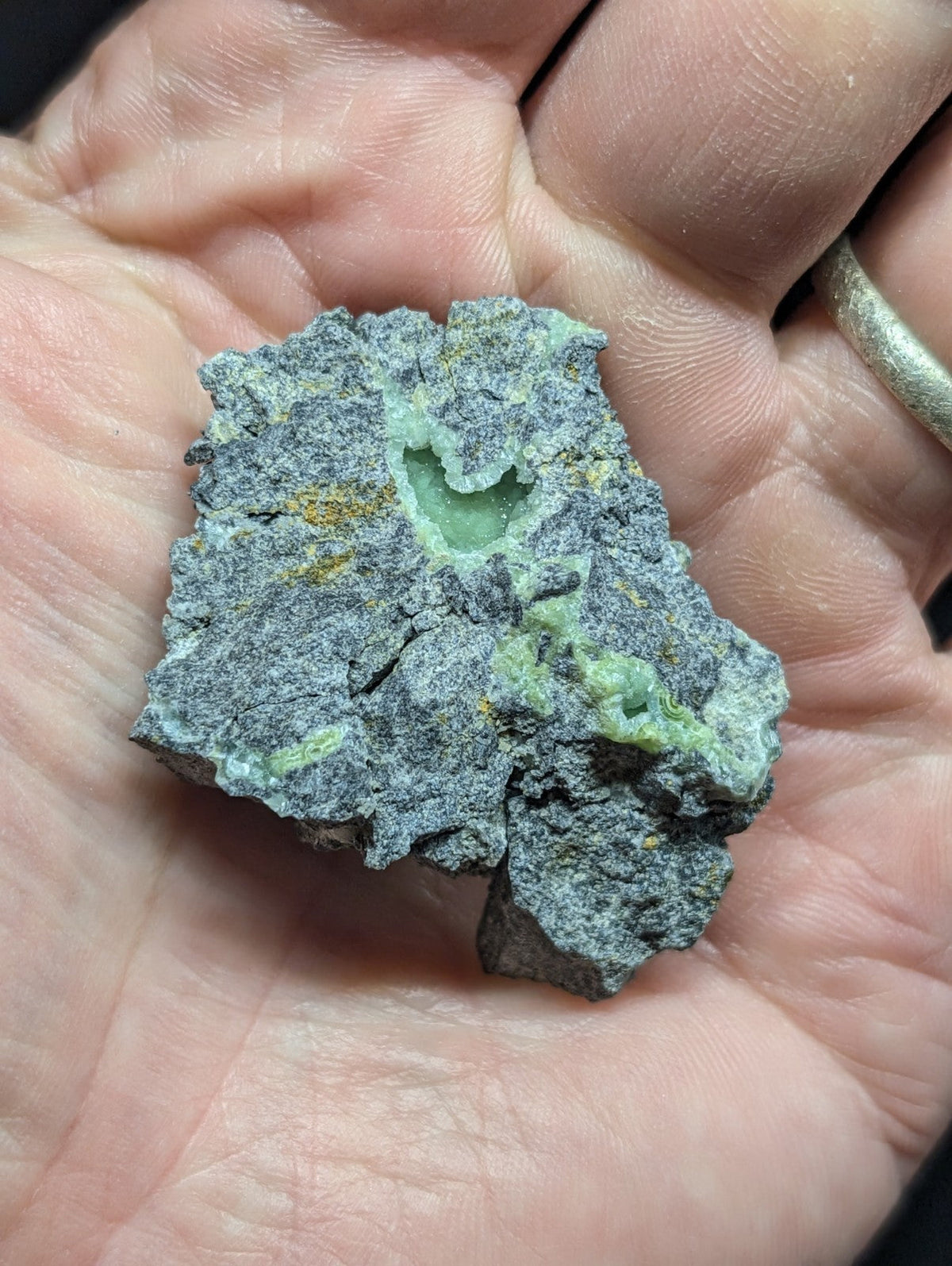 A rough, irregularly shaped mineral specimen with a grayish matrix and patches of vibrant green veining.