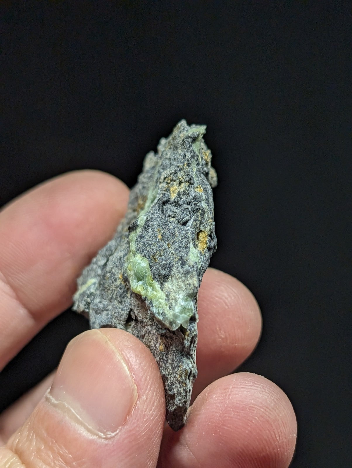 A weathered, irregularly shaped mineral specimen with a grayish surface and patches of green patina.