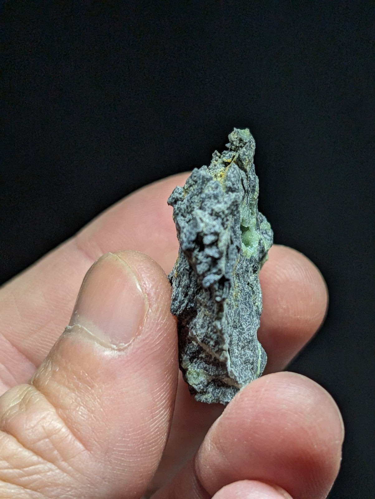A weathered, irregularly shaped mineral specimen with a mottled green and gray patina.