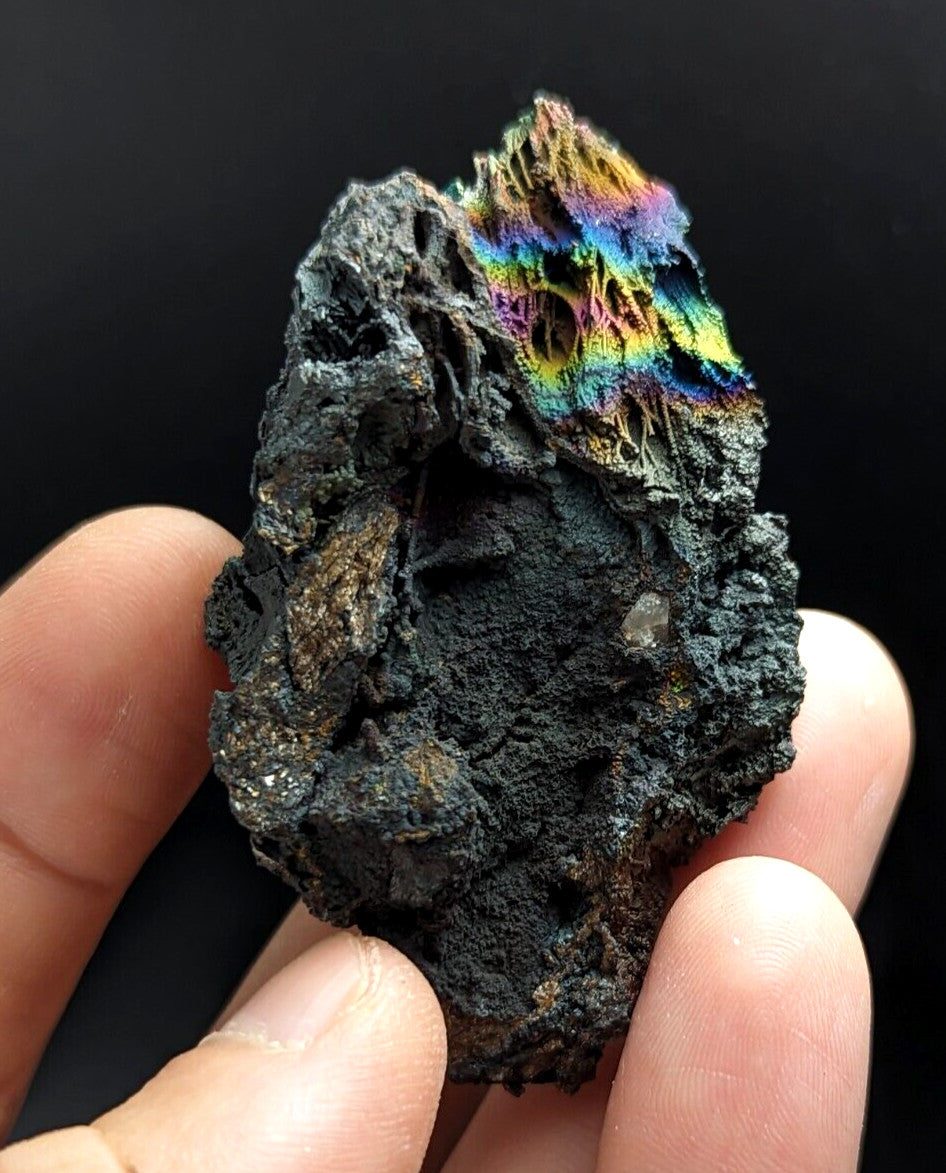 A striking black mineral specimen with a vibrant, iridescent rainbow pattern on its surface.