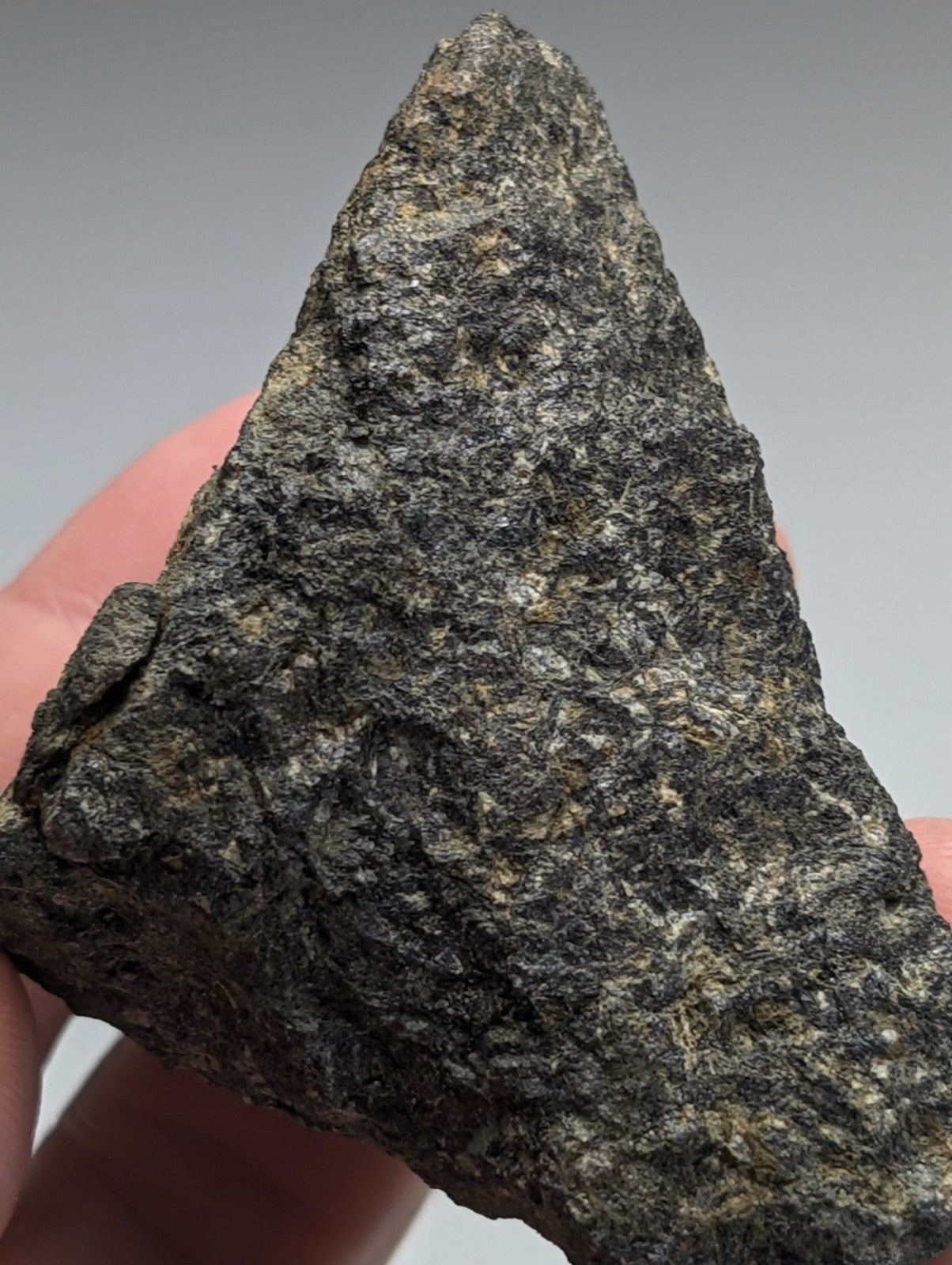 A rugged triangular-shaped jacupirangite rock with a dark gray and black speckled surface from magnet cove arkansas