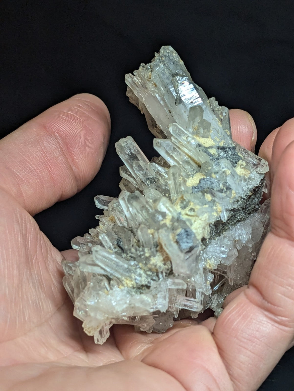 A cluster of translucent, clear quartz crystals with subtle yellow and gray mineral inclusions.