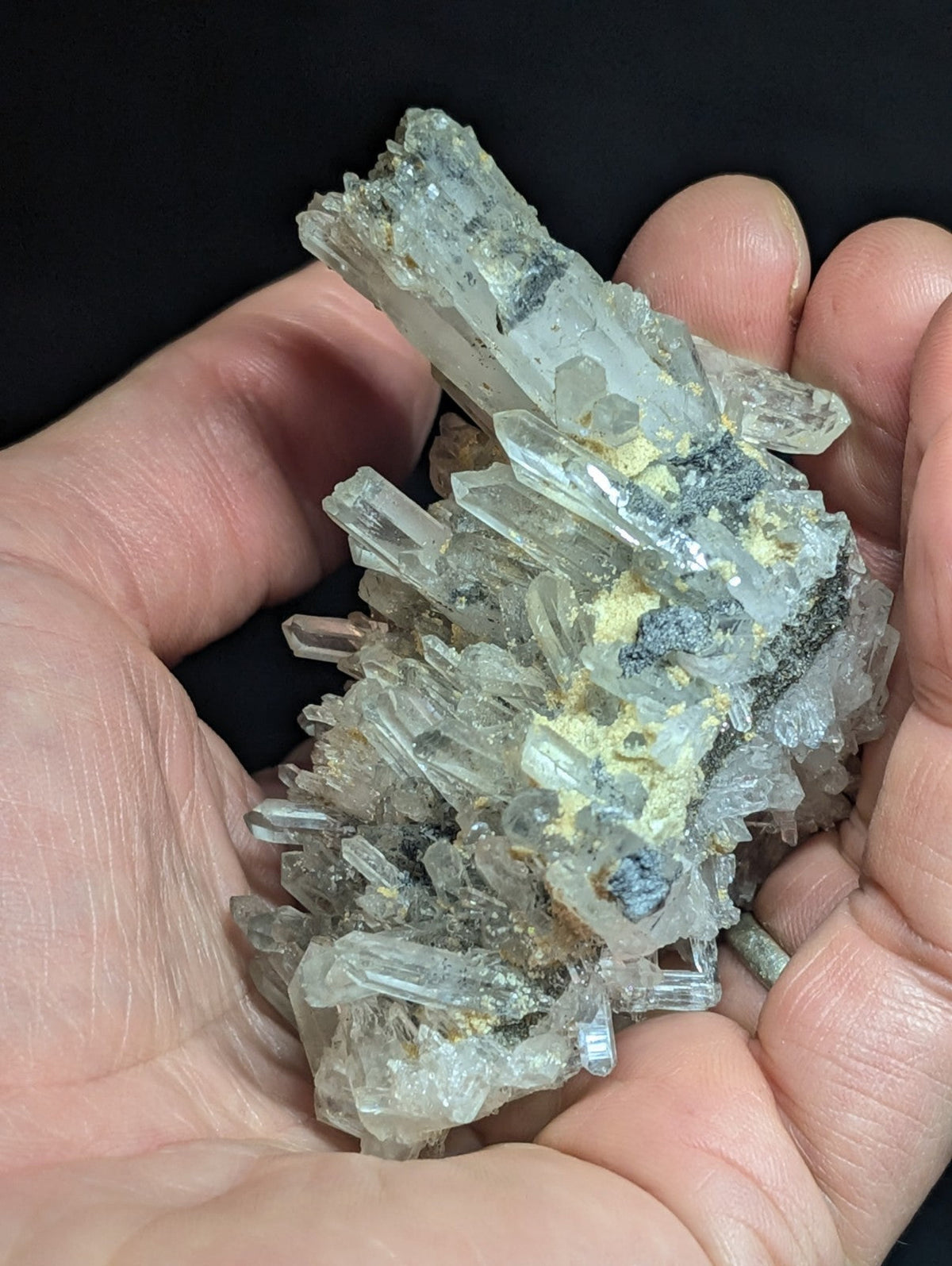 A cluster of translucent, clear quartz crystals with subtle gray and yellow mineral inclusions.