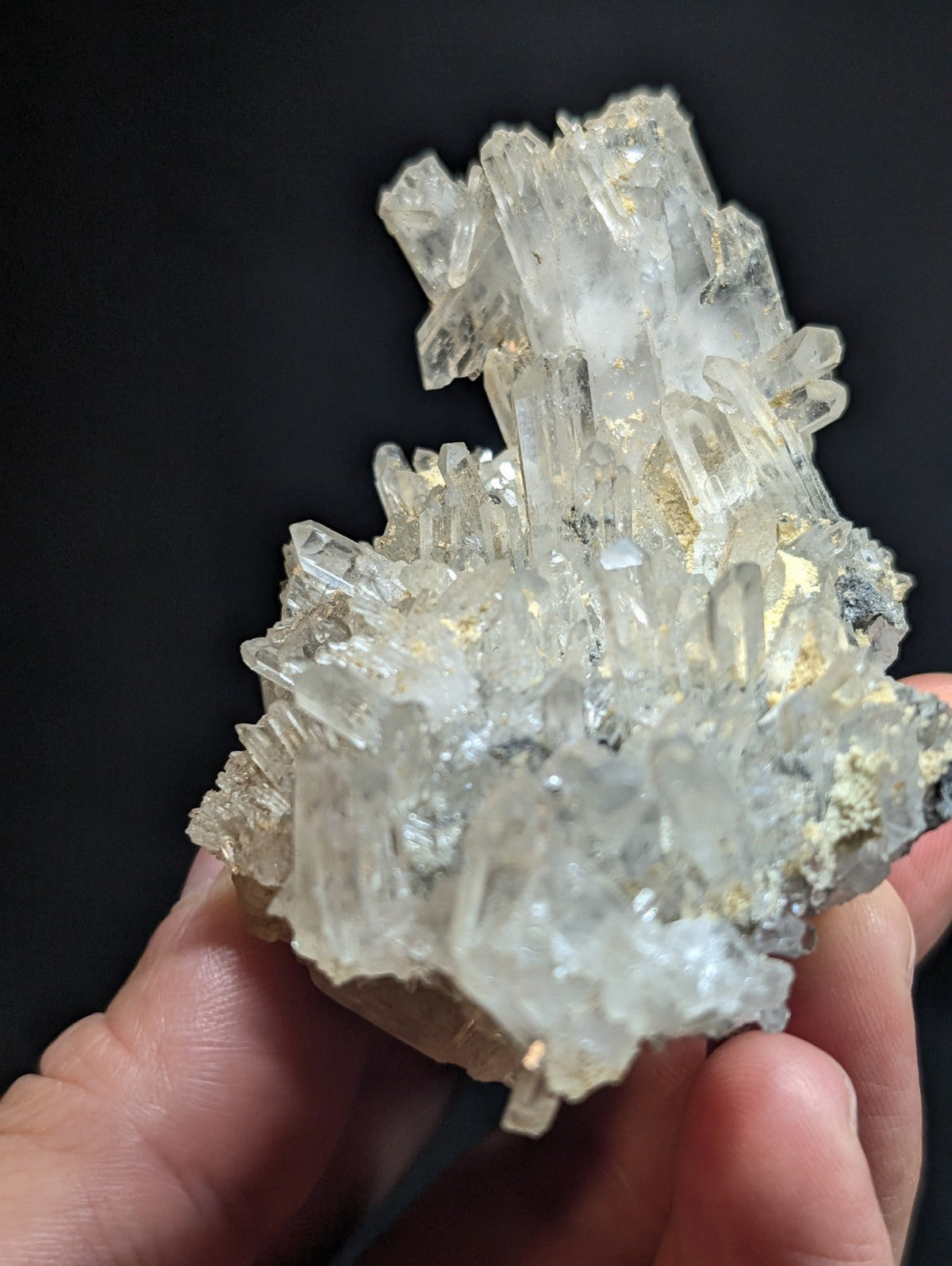 A translucent, clear quartz crystal cluster with sharp, pointed formations and subtle golden inclusions.