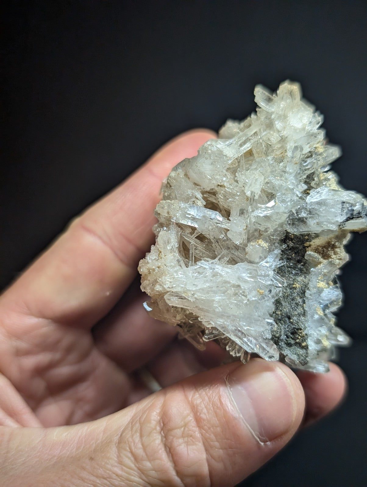 A translucent, crystalline mineral specimen with clear and slightly cloudy facets, accented by dark veining.