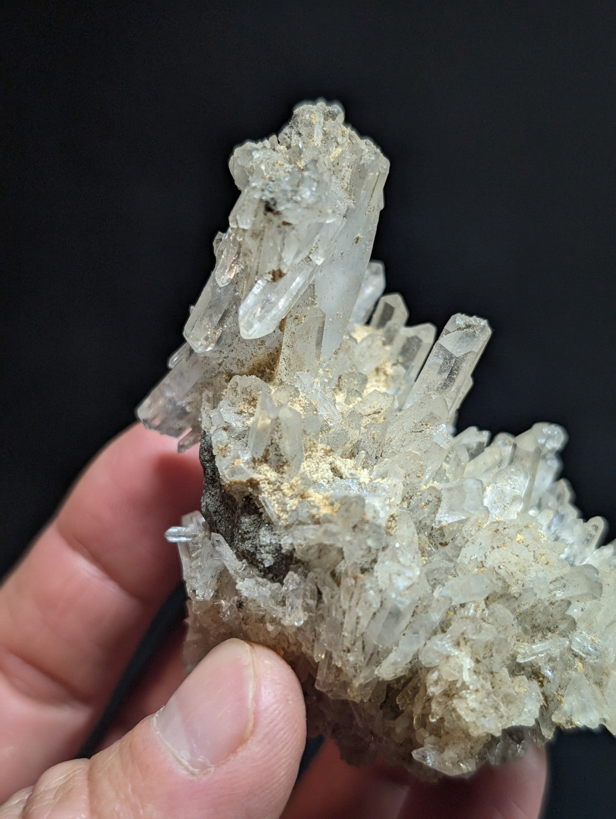 A translucent, clear quartz crystal cluster with sharp, pointed facets and a slightly golden-tinted base.