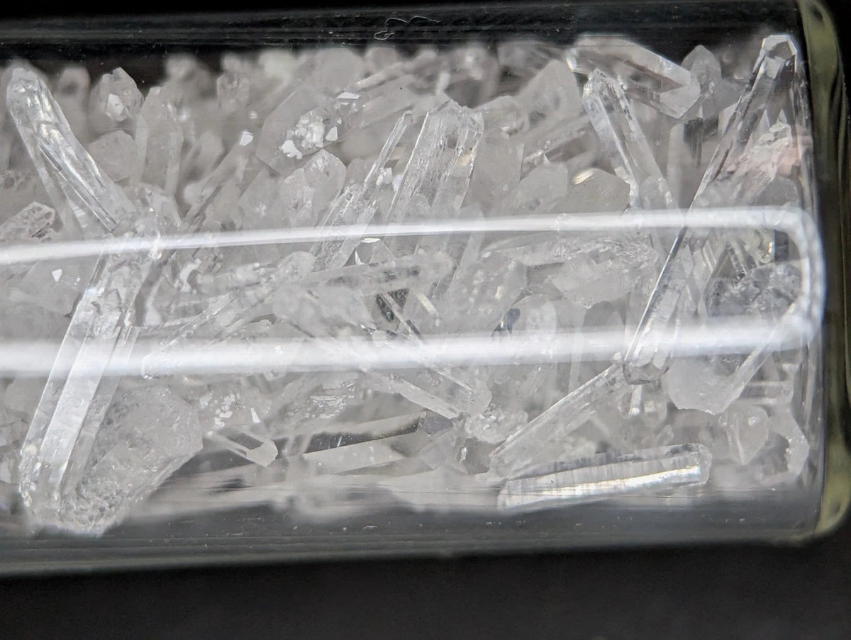 Clear quartz crystals in a transparent container.