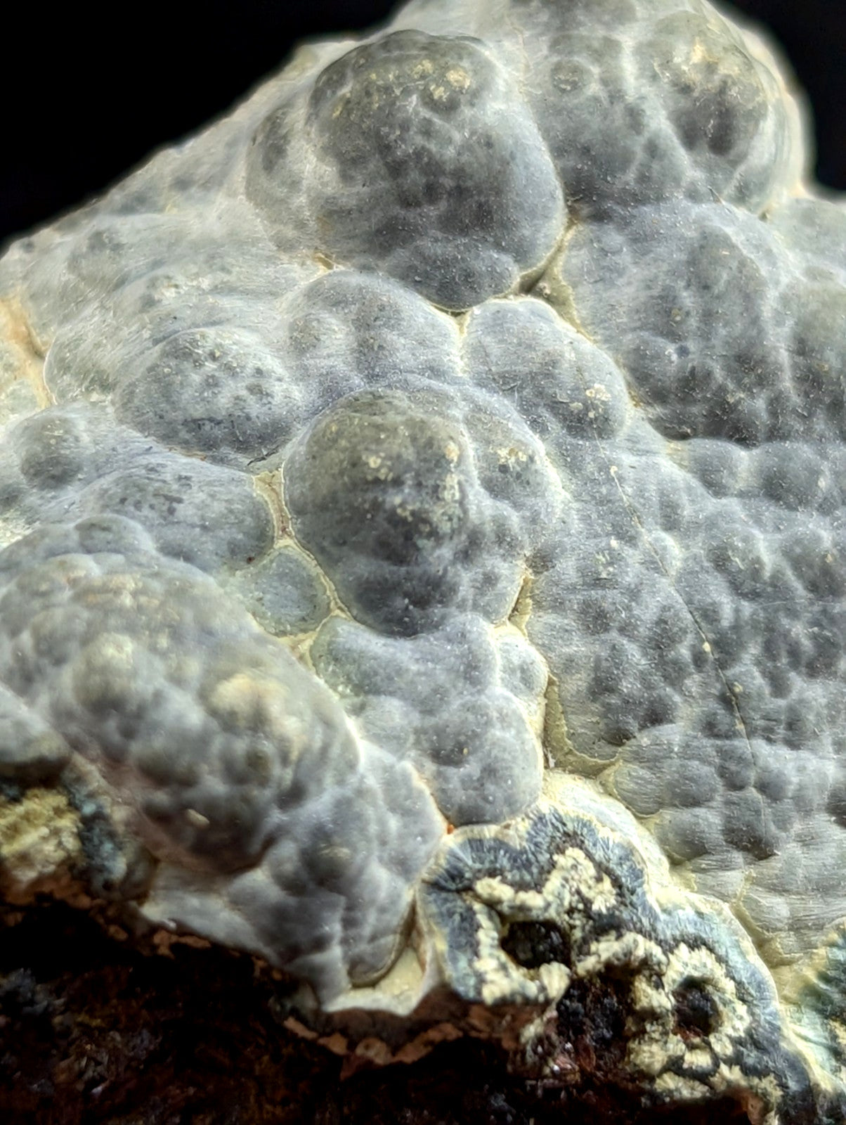 Gray, bumpy mineral specimen with a textured surface and subtle greenish-yellow accents.
