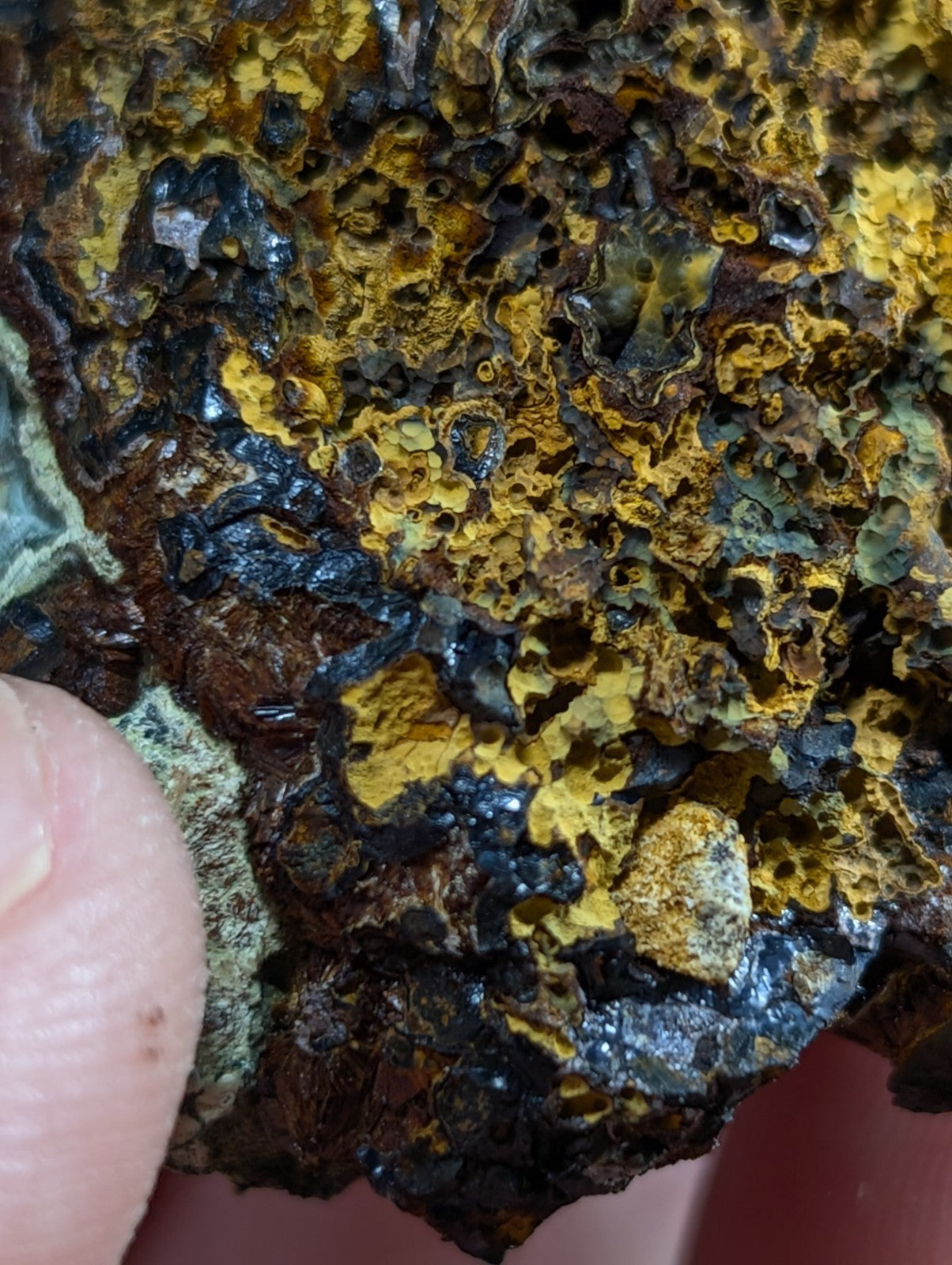 A rugged, textured mineral specimen featuring vibrant yellow and deep black patches with a rough, porous surface.