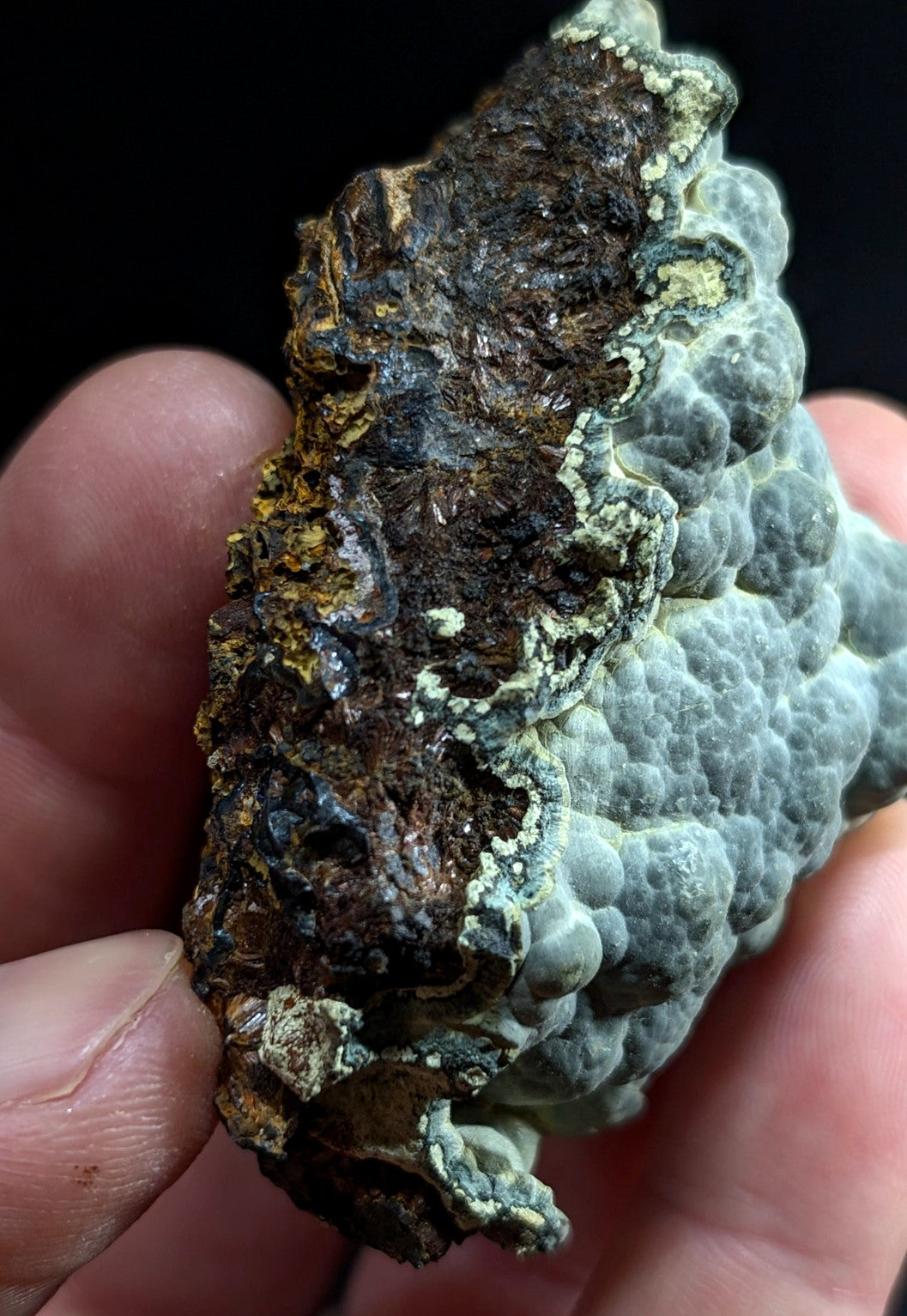 A rugged, irregularly shaped piece of mineral with a textured surface featuring patches of dark brown and grayish-blue hues.