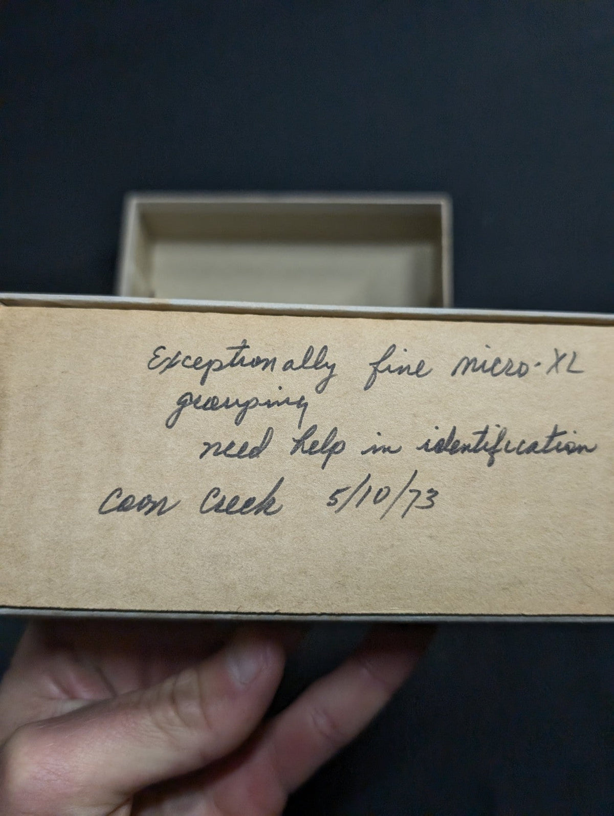 A handwritten note on aged, beige cardboard with cursive script.