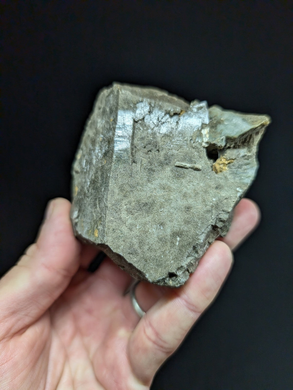 A rough, irregularly shaped piece of grayish metallic mineral with visible crystalline facets and minor yellow inclusions.