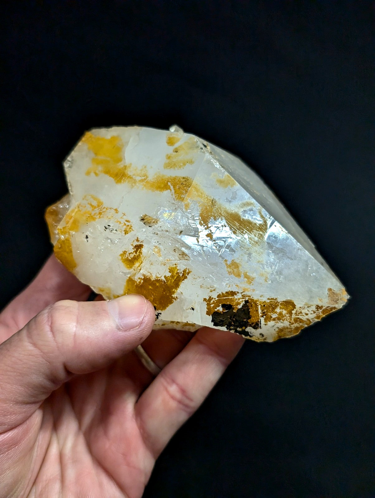A translucent white quartz crystal with golden-yellow inclusions and a rough, natural edge.