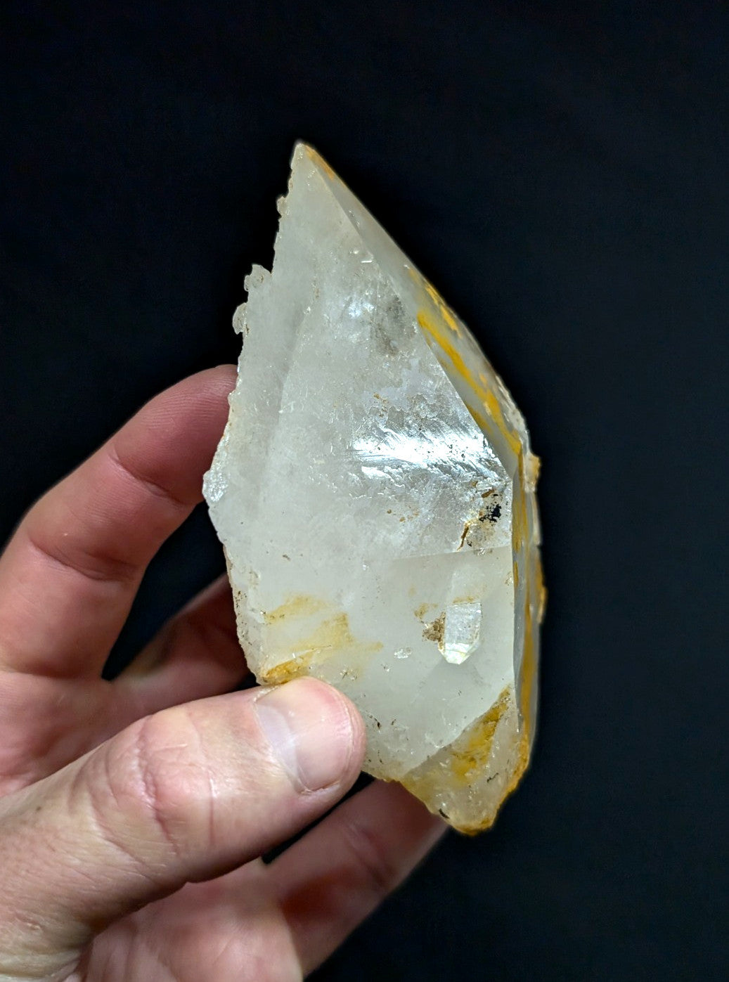 A translucent white quartz crystal with yellowish inclusions and a rough, jagged surface.