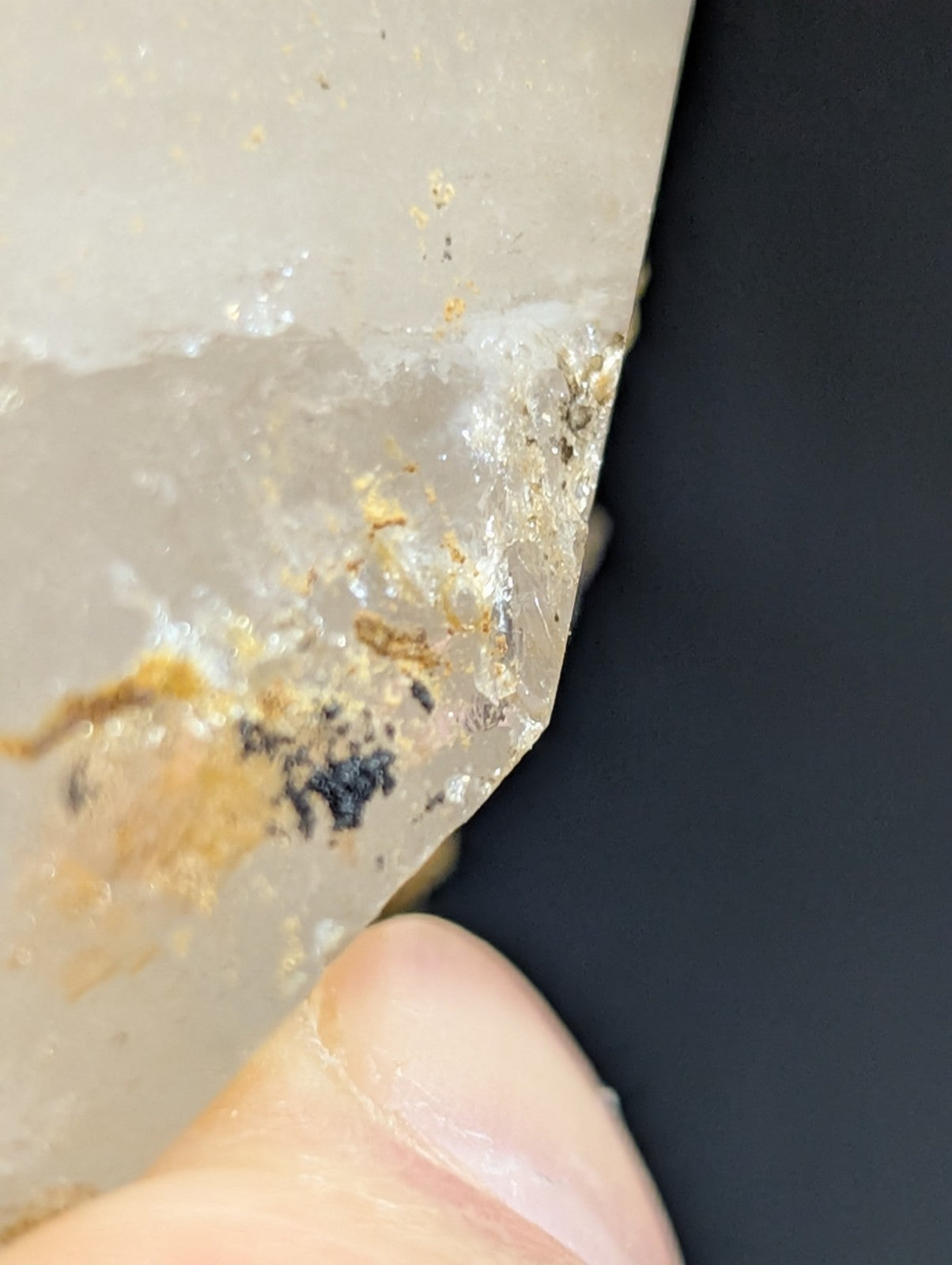 A translucent, pale quartz crystal with natural inclusions of golden and dark mineral streaks.