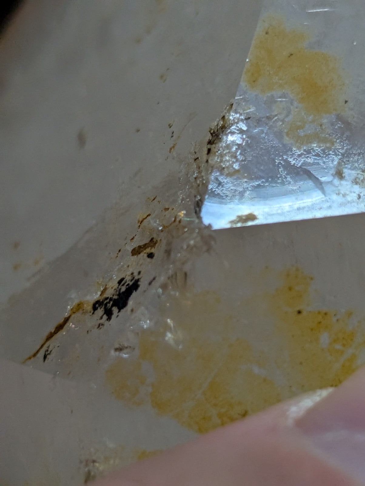 A translucent, crystalline mineral specimen with embedded golden and dark inclusions.