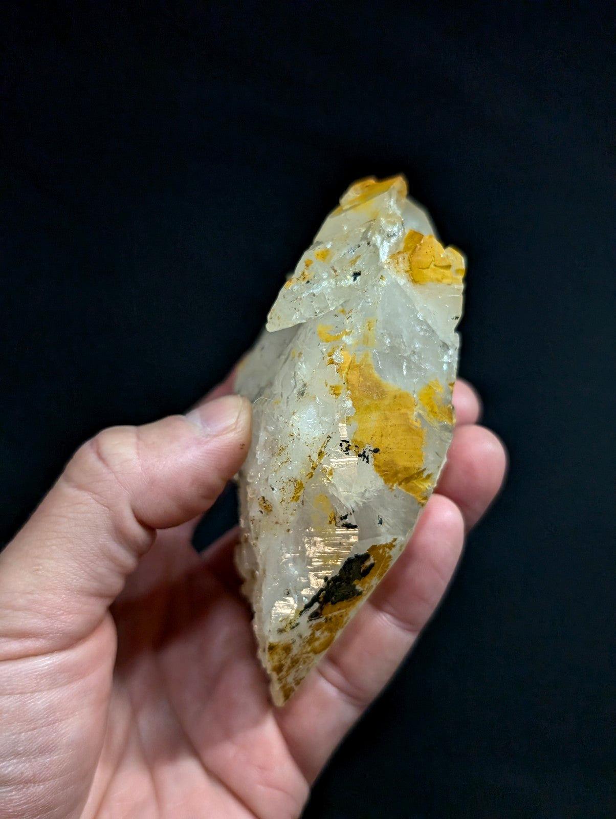 A translucent, pale yellow and white crystal with golden-yellow inclusions held gently in a hand.