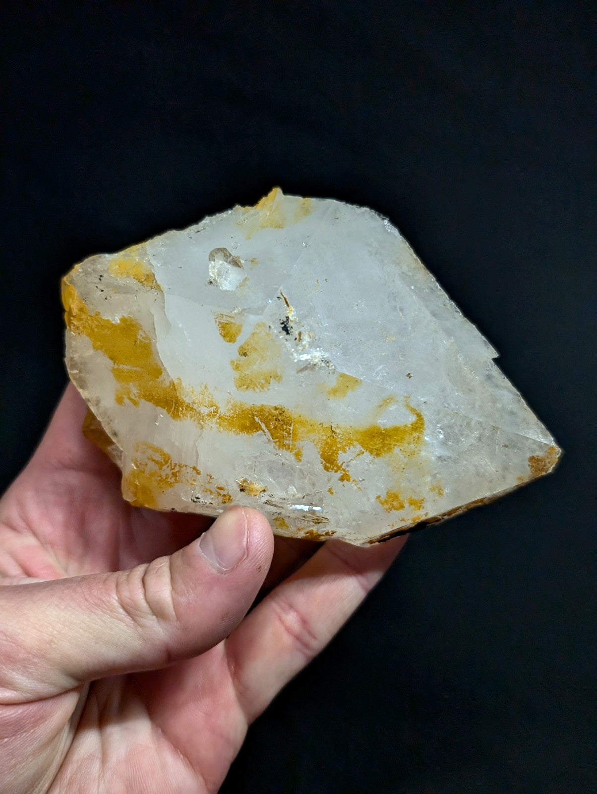 A translucent white crystal with golden-yellow inclusions and a rough, jagged surface.