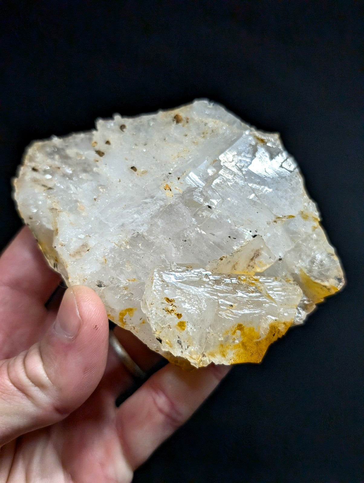 A translucent, crystalline mineral specimen with a rough, jagged surface and golden-yellow streaks along its edges.
