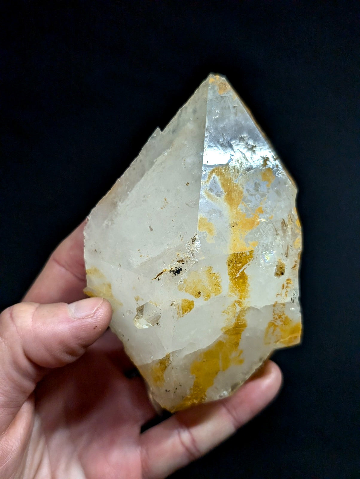 A translucent, faceted quartz crystal with golden-yellow inclusions and a pointed tip.