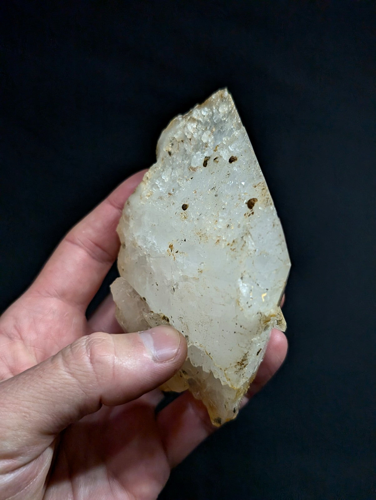 A translucent, pale white quartz crystal with a rough, jagged surface and subtle golden inclusions.