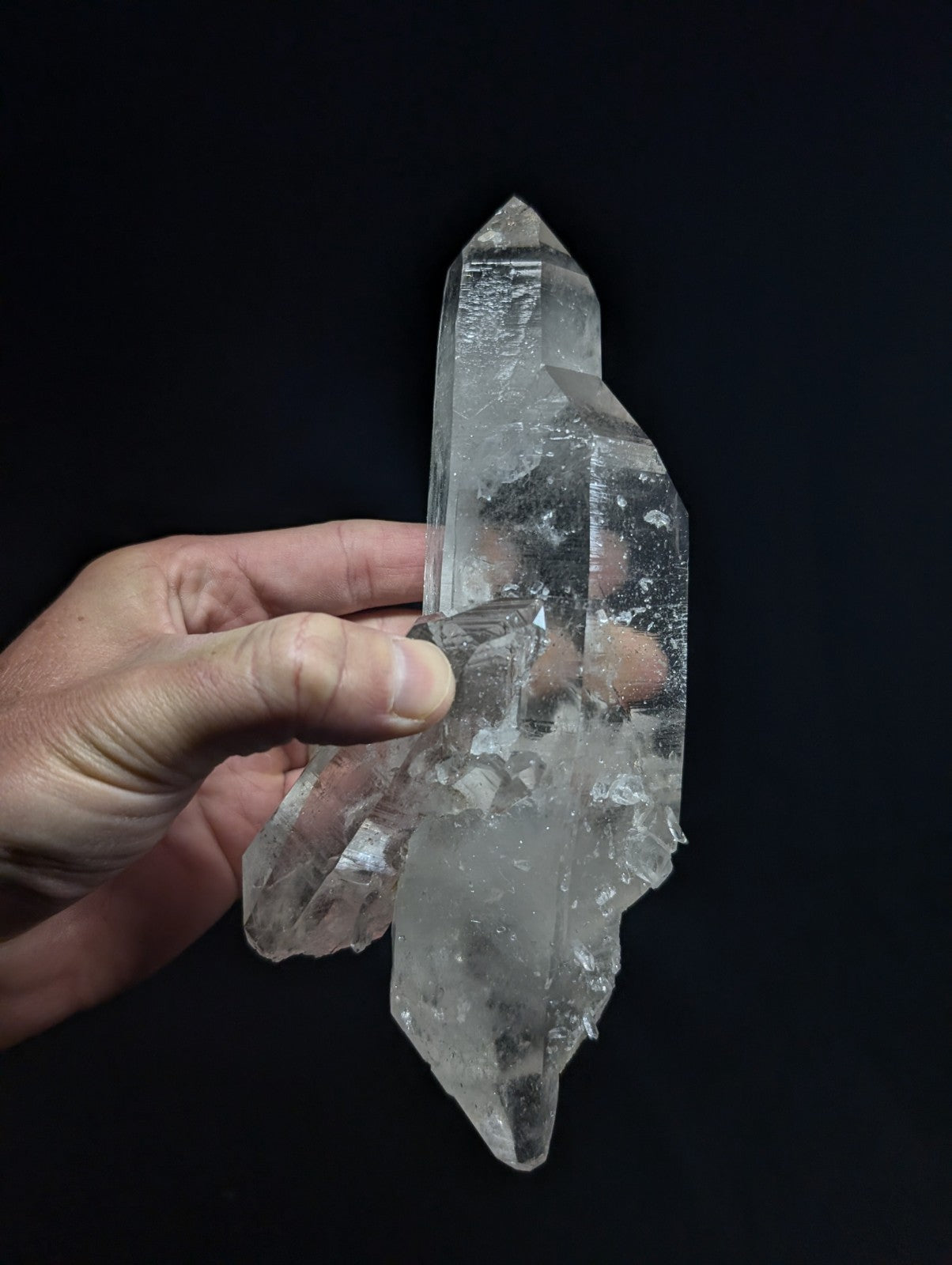 A clear, translucent quartz crystal cluster with sharp facets and a pointed tip.