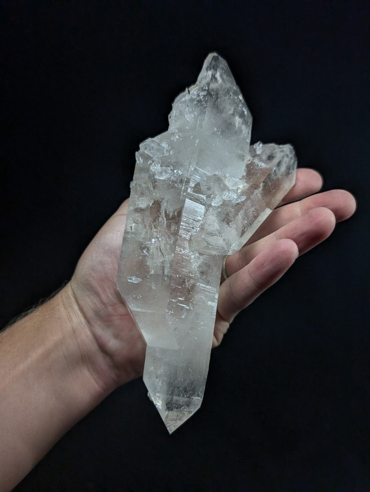 A translucent, clear quartz crystal cluster with sharp geometric facets and a natural, jagged growth pattern.