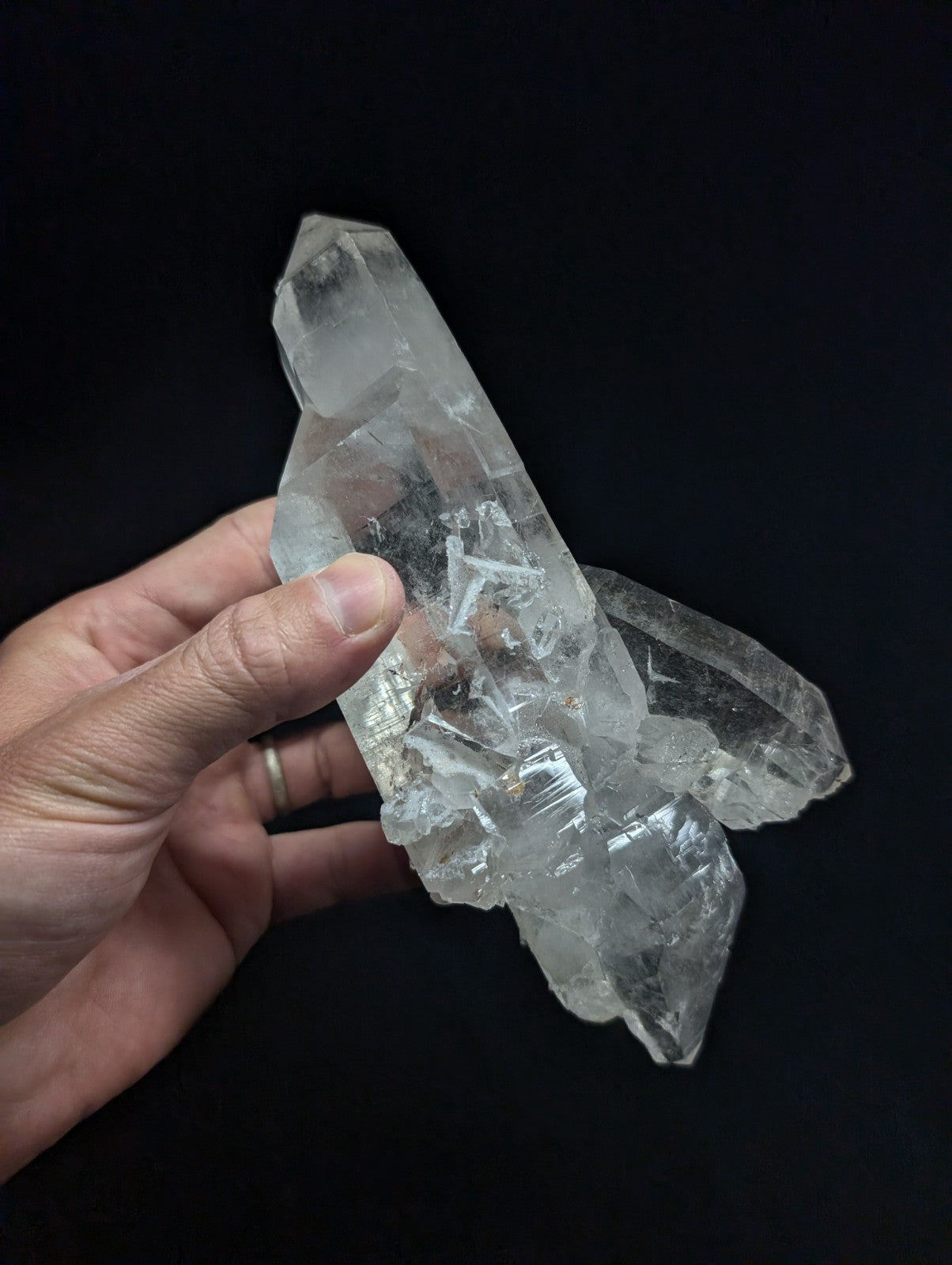 A clear, translucent quartz crystal cluster with sharp geometric facets and natural internal inclusions.