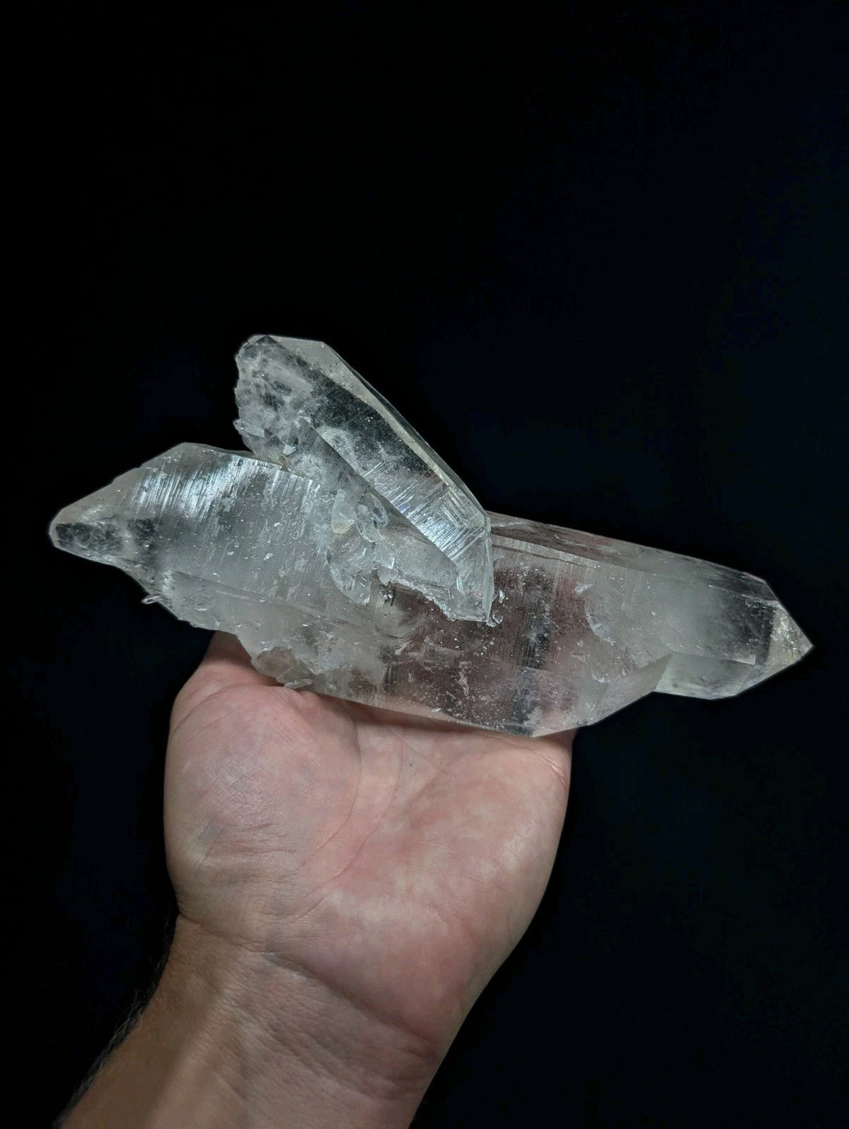 A translucent, clear quartz crystal cluster with sharp facets and natural imperfections.