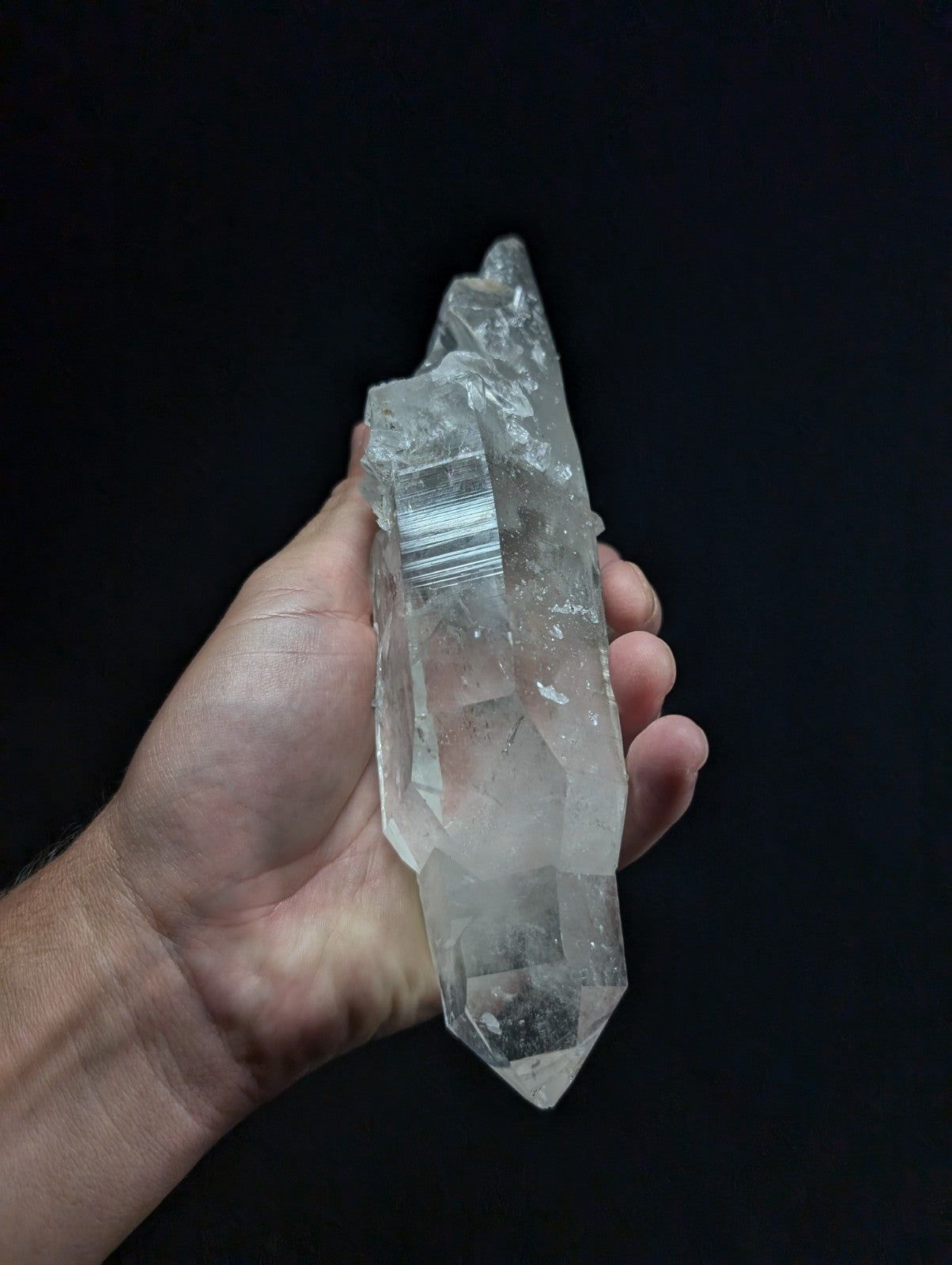 A translucent, clear quartz crystal with a pointed tip and visible internal striations.