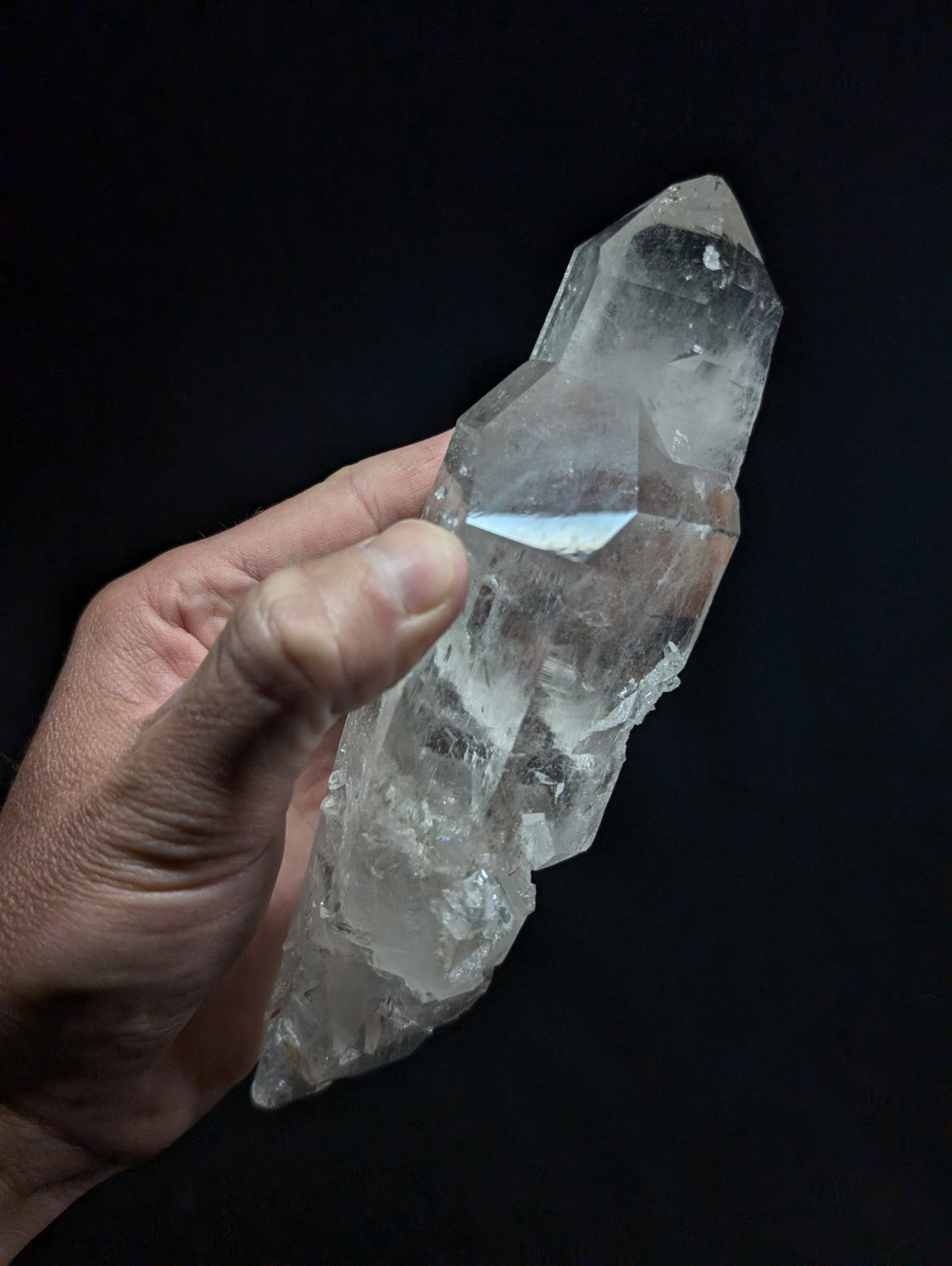 A clear, translucent quartz crystal with a pointed tip and natural facets.