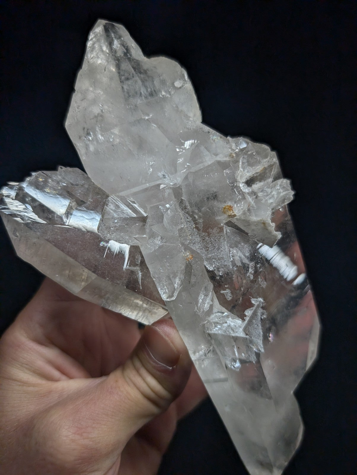 A translucent, clear quartz crystal cluster with sharp geometric facets and natural imperfections.