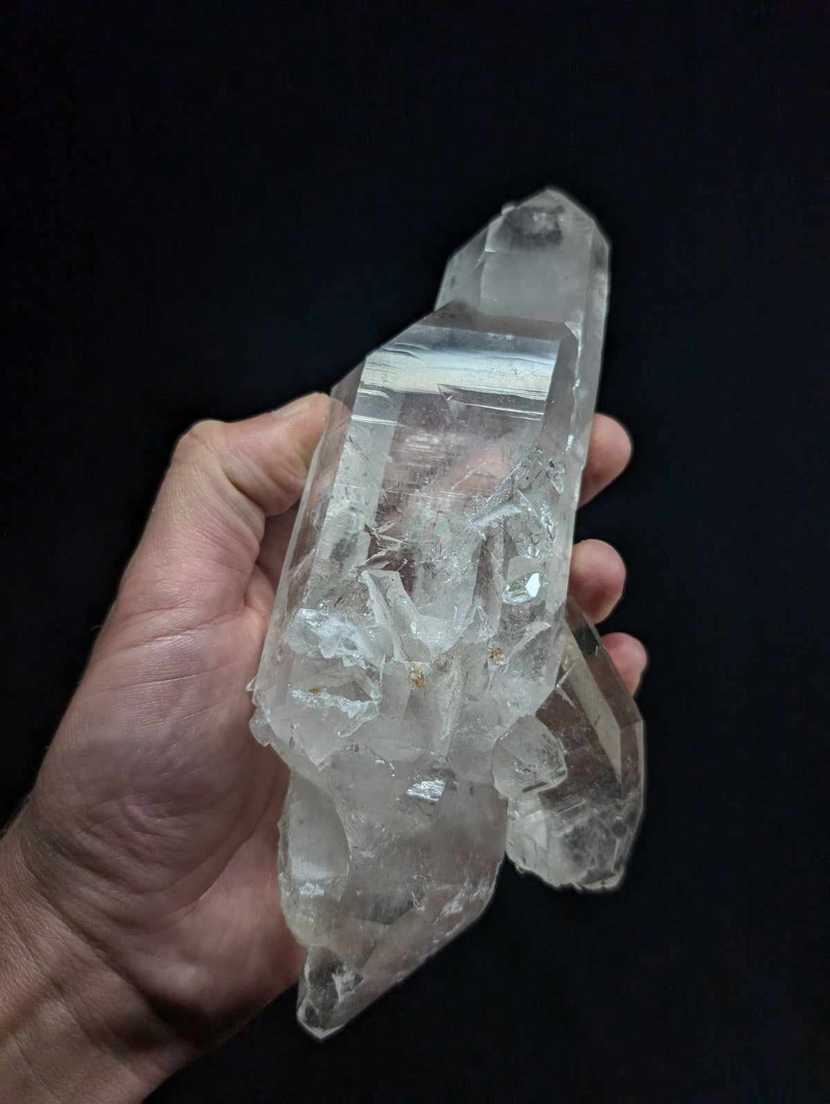 A clear, translucent quartz crystal cluster with sharp facets and natural inclusions.