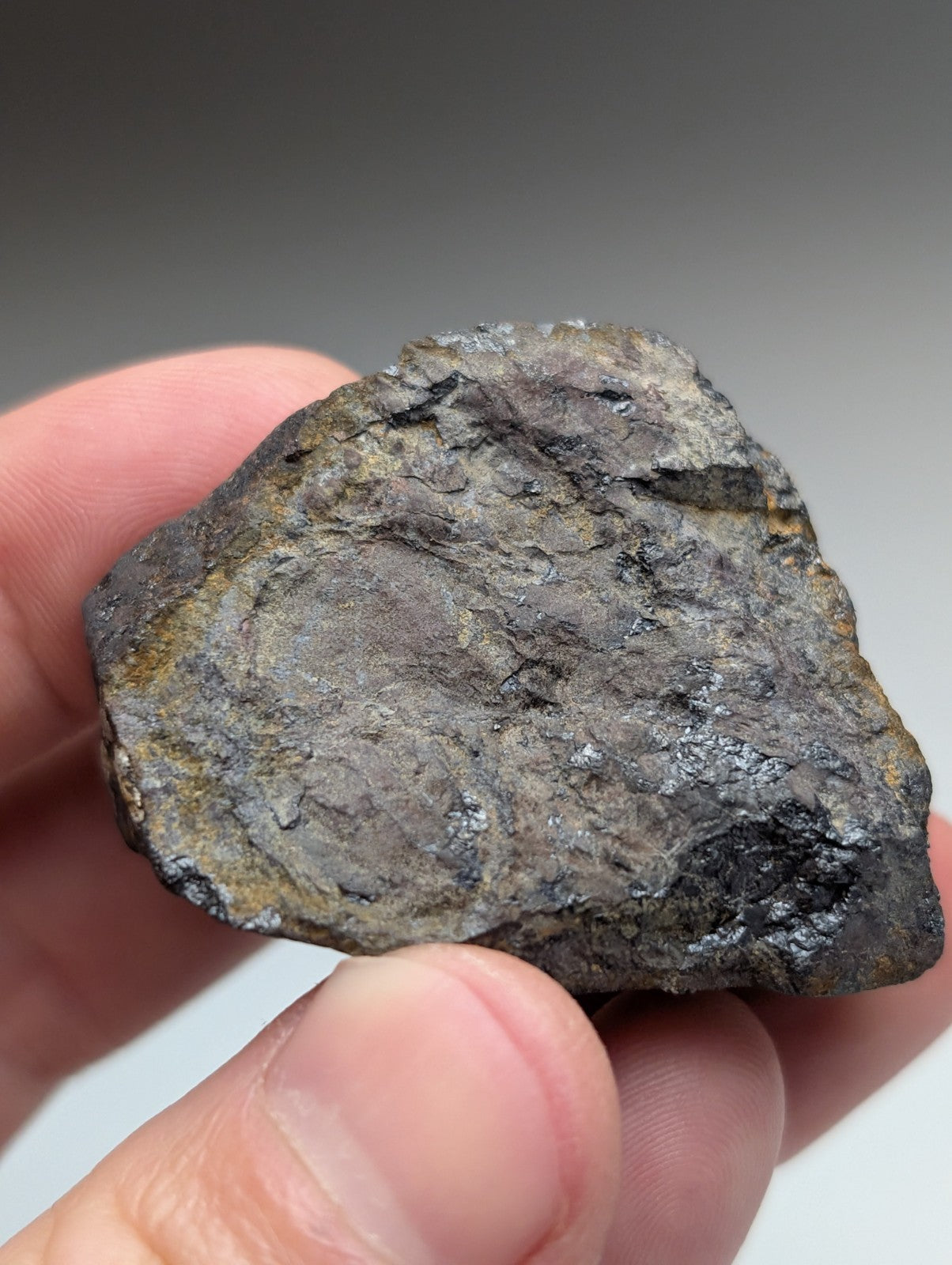 A rugged magnetite lodestone meteorite from Magnet Cove Arkansas with dark gray metallic surface and yellowish oxidation patches