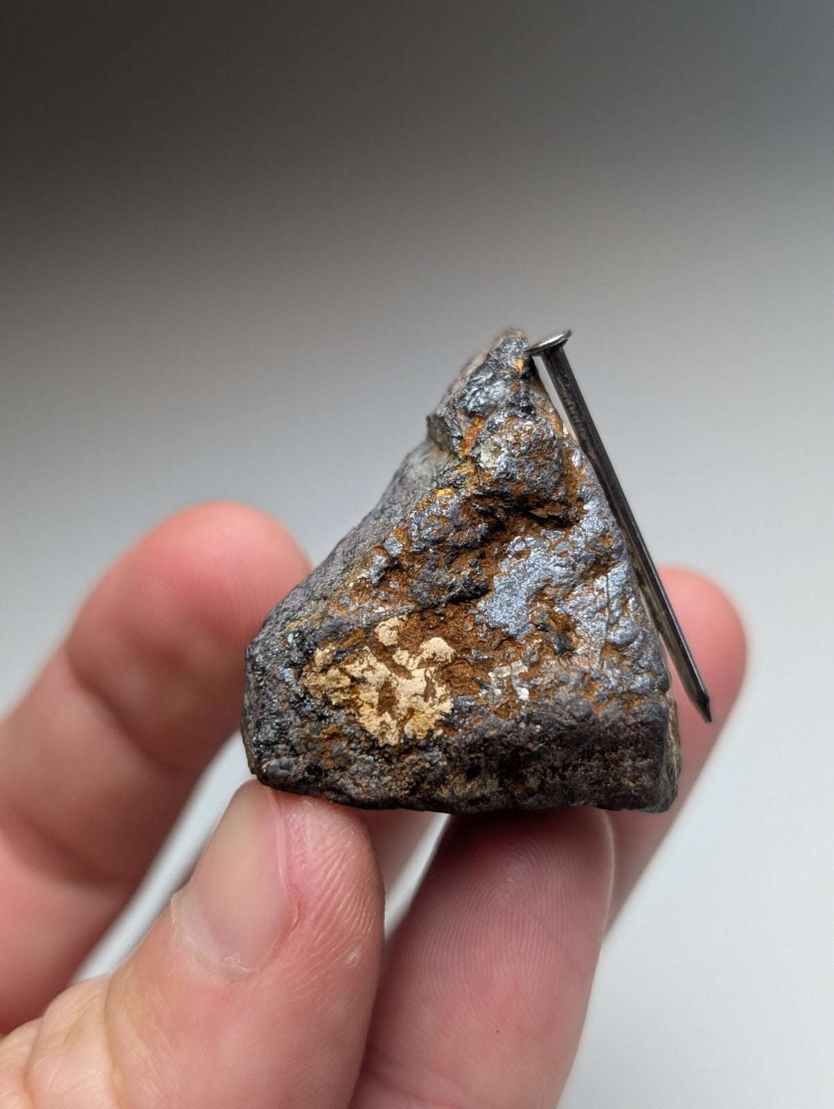 A rugged triangular magnetite lodestone meteorite with dark gray and orange metallic surface from Magnet Cove Arkansas