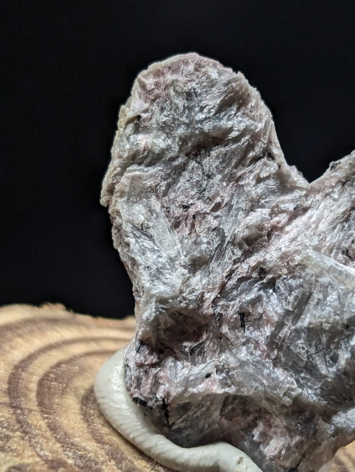 A rugged, grayish-white mineral specimen with translucent crystalline formations and subtle pinkish hues.