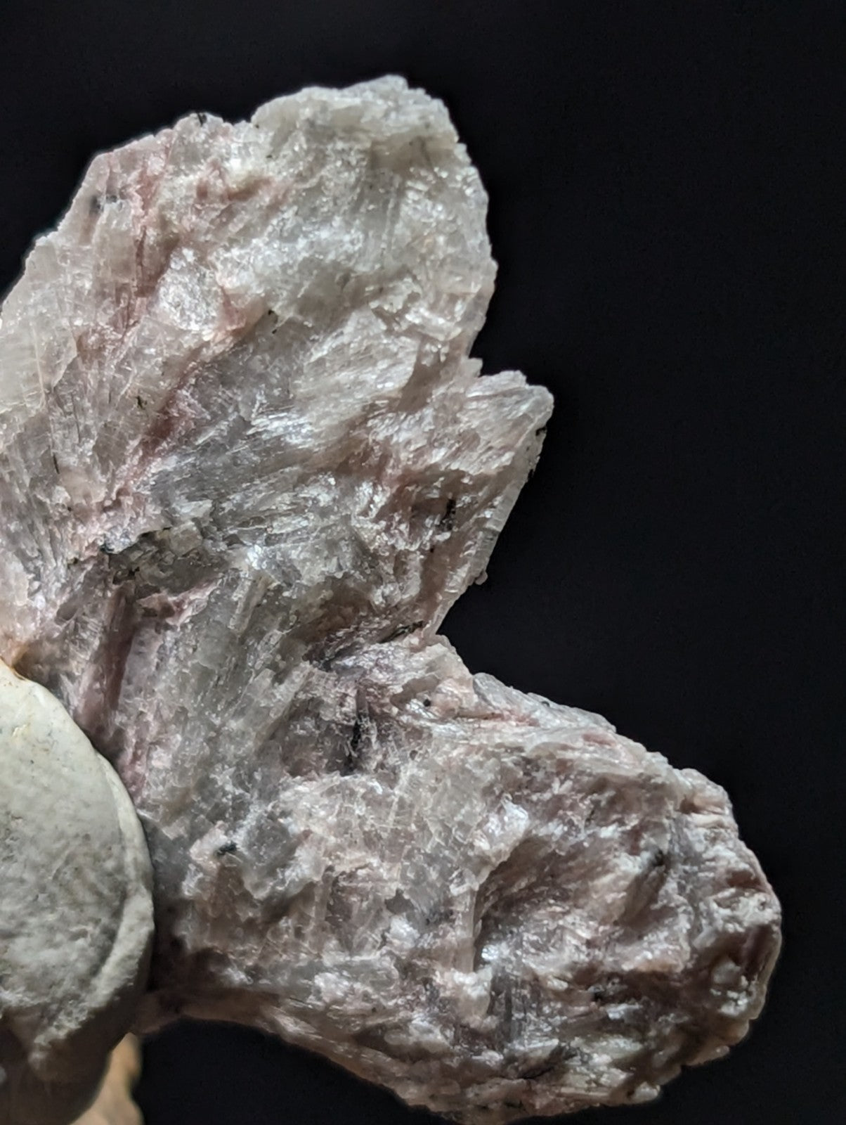 A rough, translucent pinkish-white mineral specimen with visible crystalline facets and a slightly jagged surface.