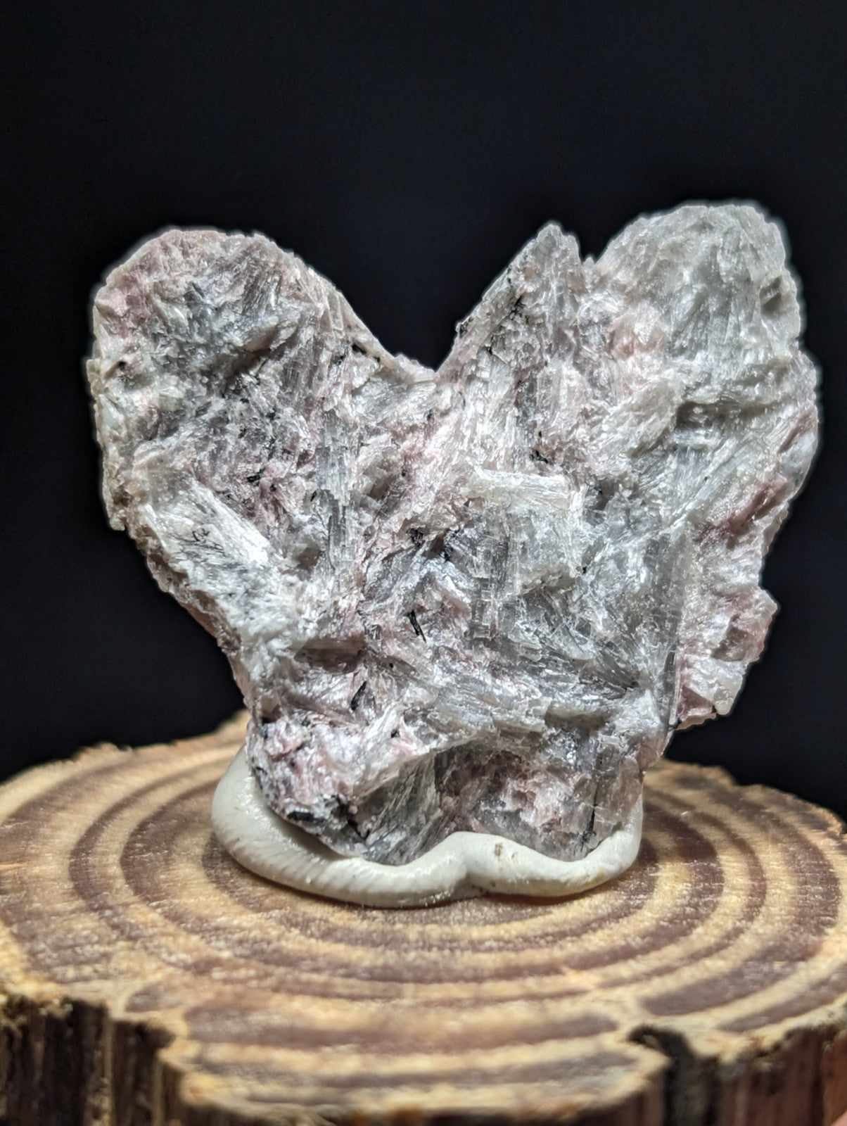 A rough, naturally formed mineral specimen with a translucent grayish-pink hue and crystalline texture.