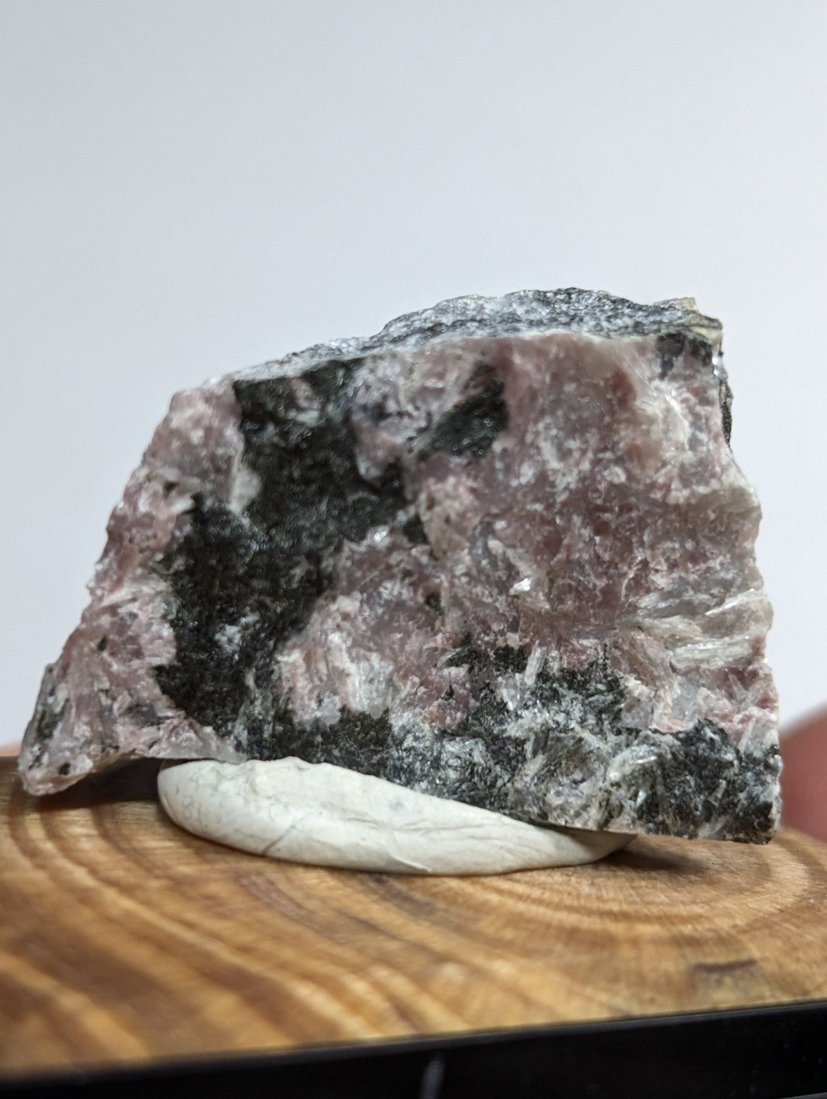 A rugged, naturally fractured rock specimen with a mottled pattern of pinkish-purple and dark gray mineral veins.