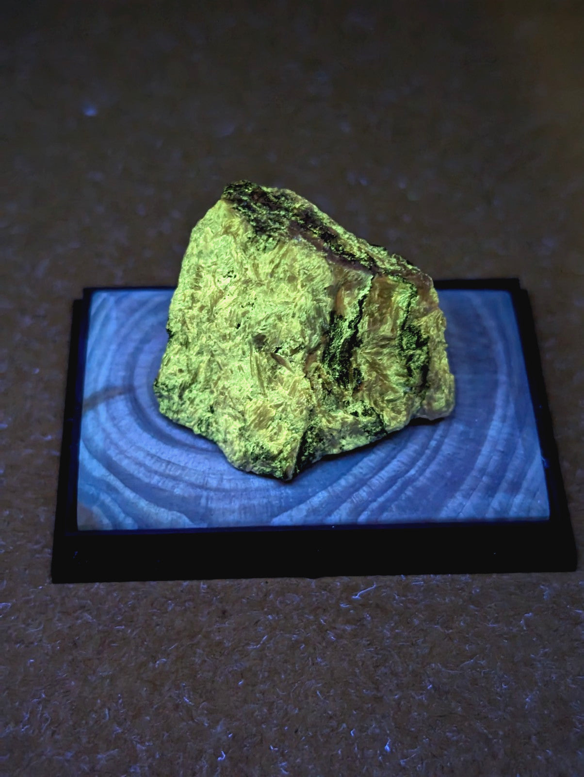 A rough, irregularly shaped piece of bright green mineral with darker streaks and a textured surface.