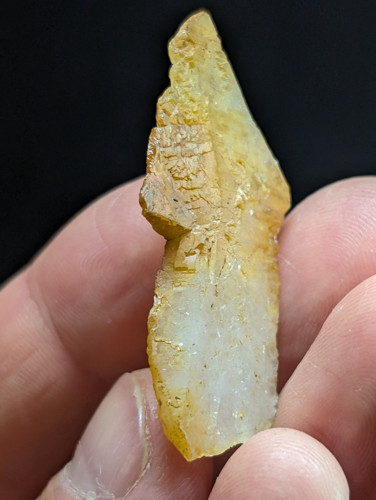 A translucent yellowish crystal with a rough, jagged surface and subtle internal striations.