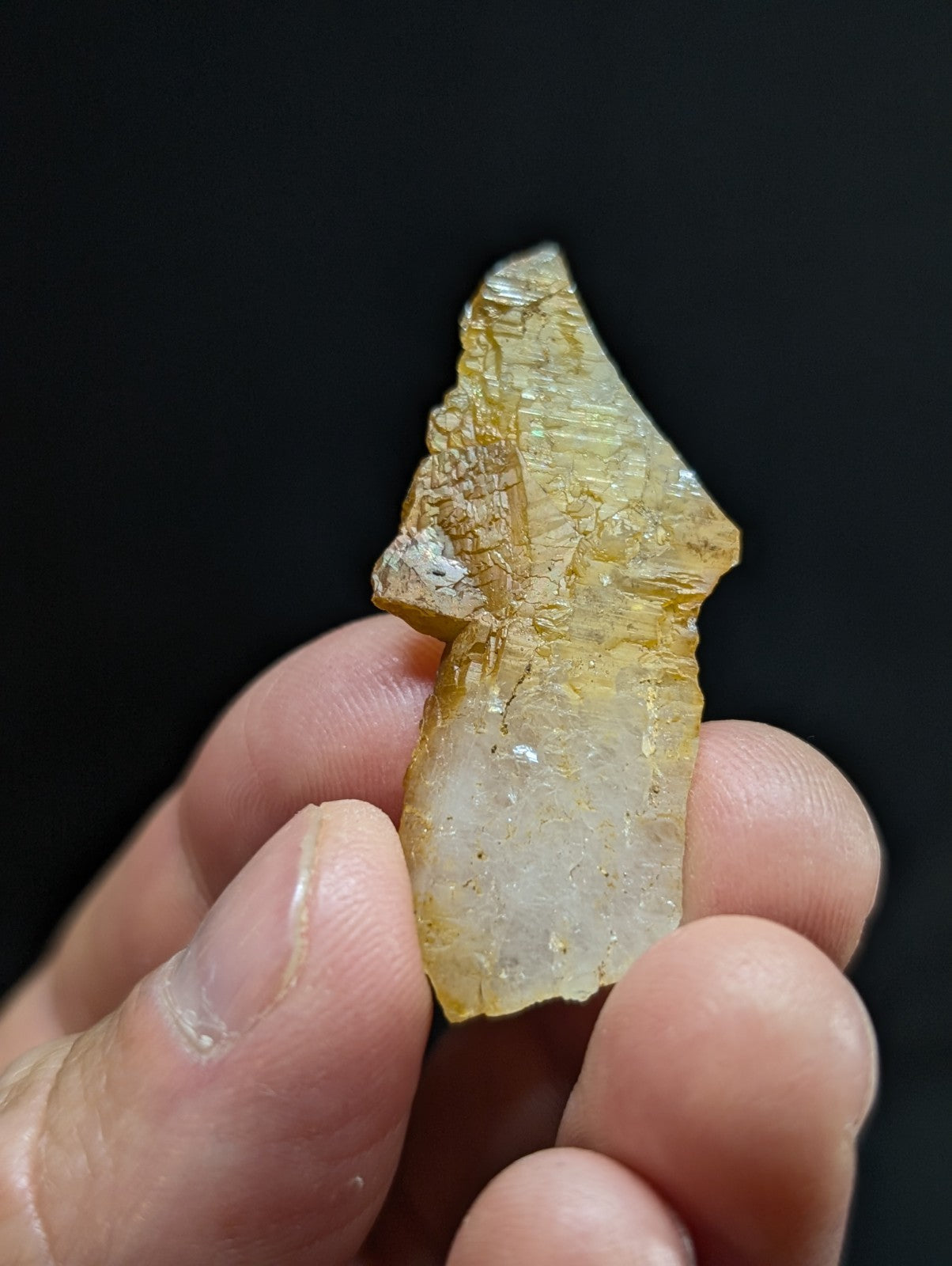A translucent yellowish crystal fragment with visible internal striations and a rough, jagged edge.