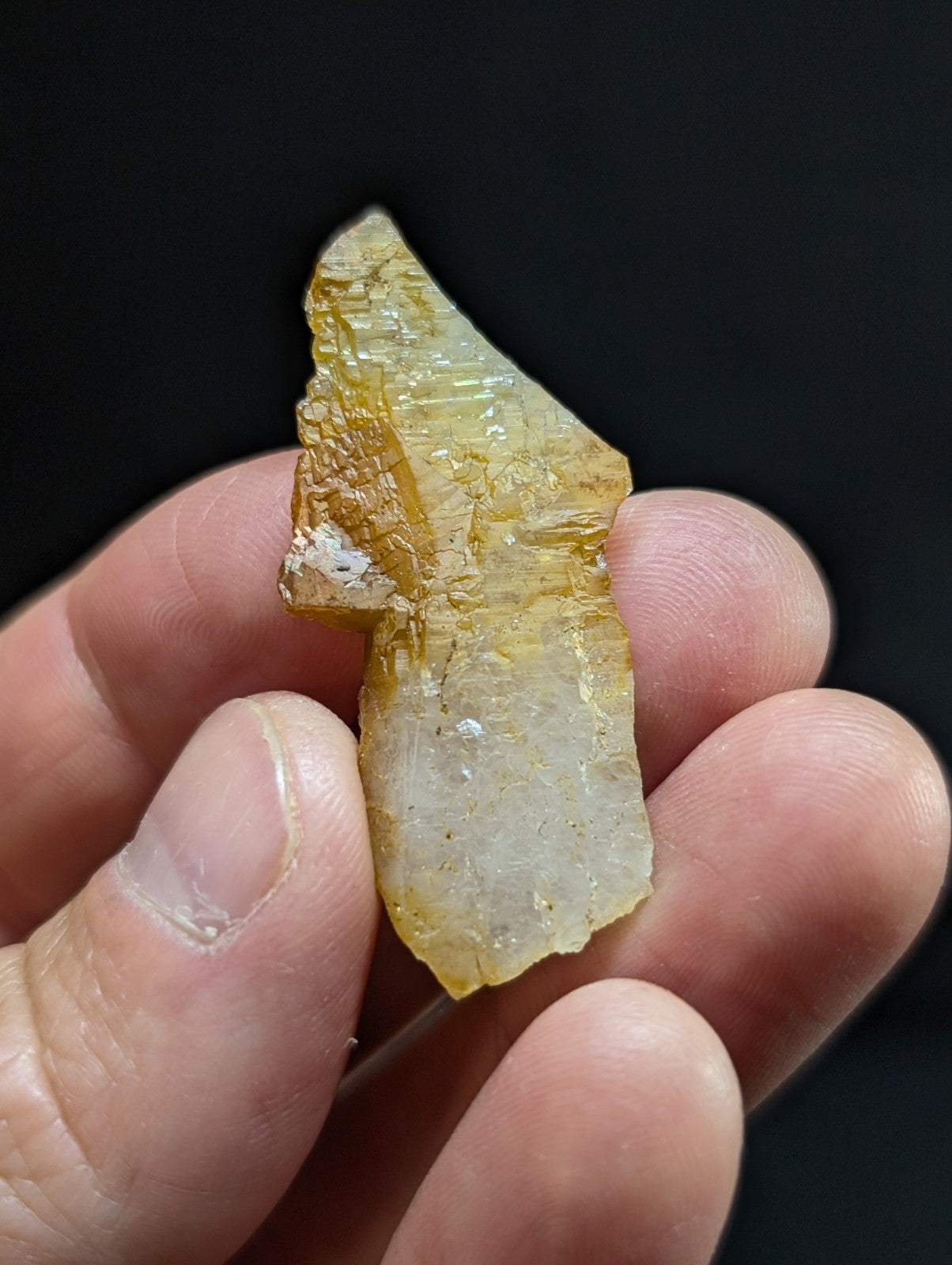 A translucent yellowish crystal fragment with visible internal striations and a rough, jagged edge.