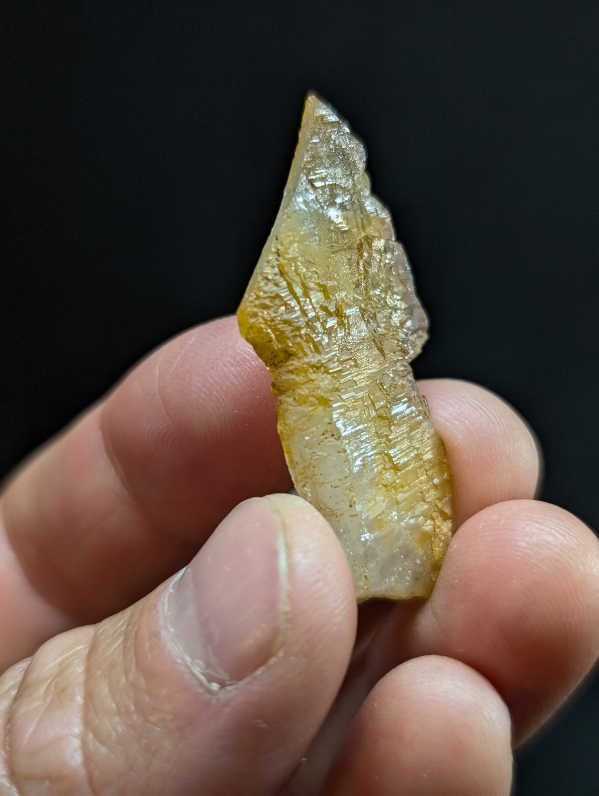 A translucent yellowish crystal with a jagged, natural edge and visible internal striations.