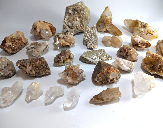 A collection of natural quartz crystals and mineral specimens, featuring translucent white to golden hues with earthy brown and gray veining.