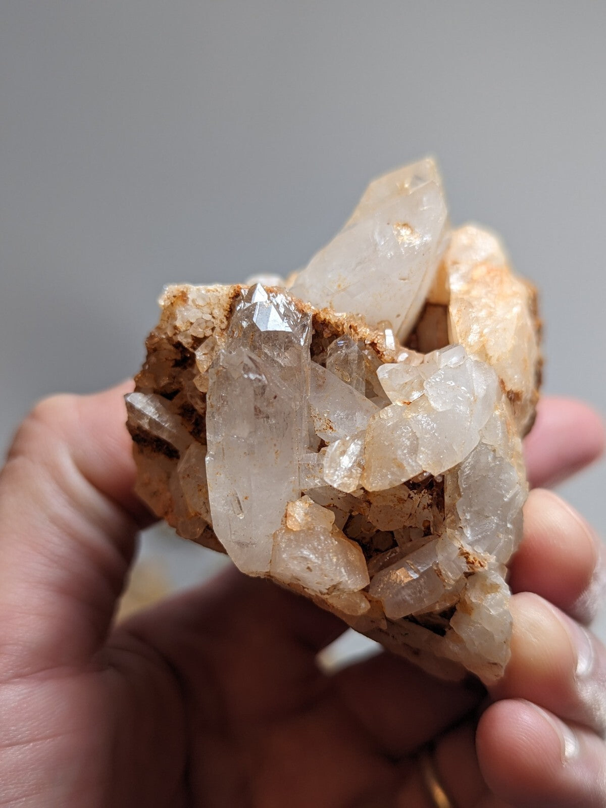 A cluster of translucent quartz crystals with clear, faceted points and a rough brown matrix base.